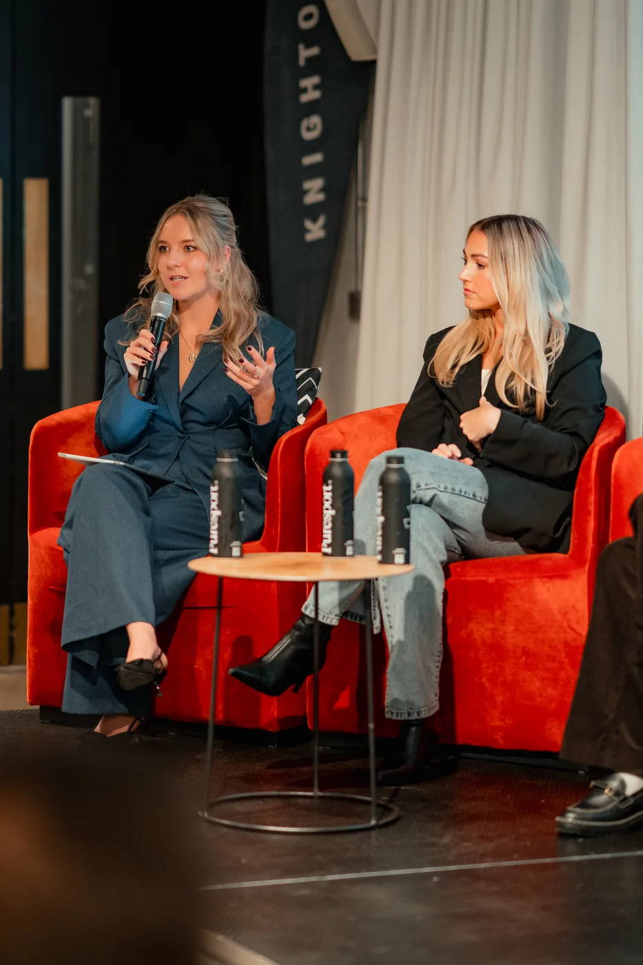 Two women speaking on stage during a panel discussion