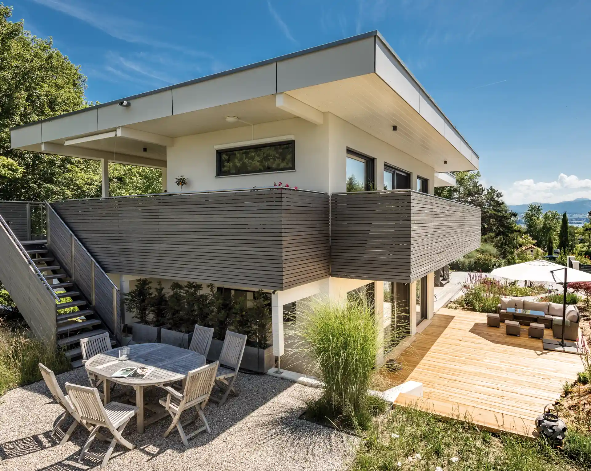 Wooden house with solar panels on the roof, surrounded by lush greenery.