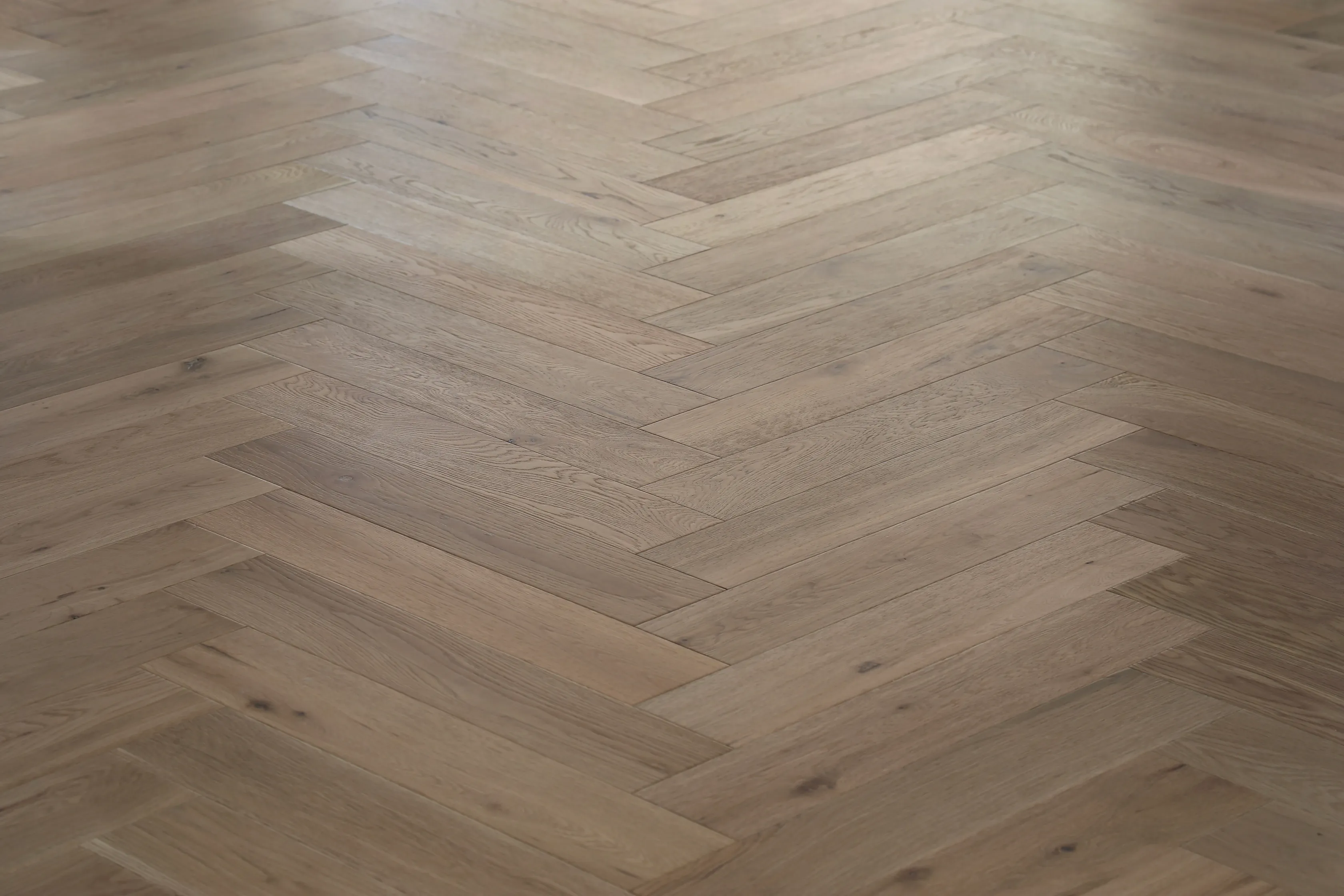 Close-up of herringbone oak flooring in warm grey-brown tones