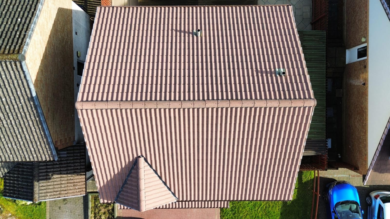 Aerial view of a house with a clean, beige tiled roof, featuring two small vents.