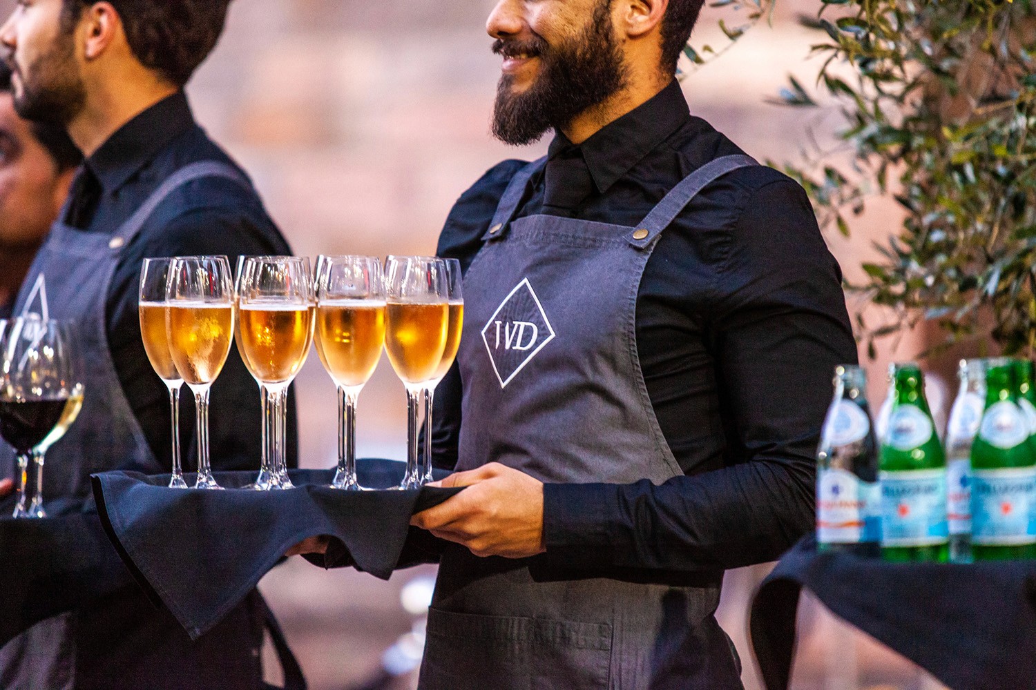 Beverage staff with arrival tray drinks including glasses of champagne