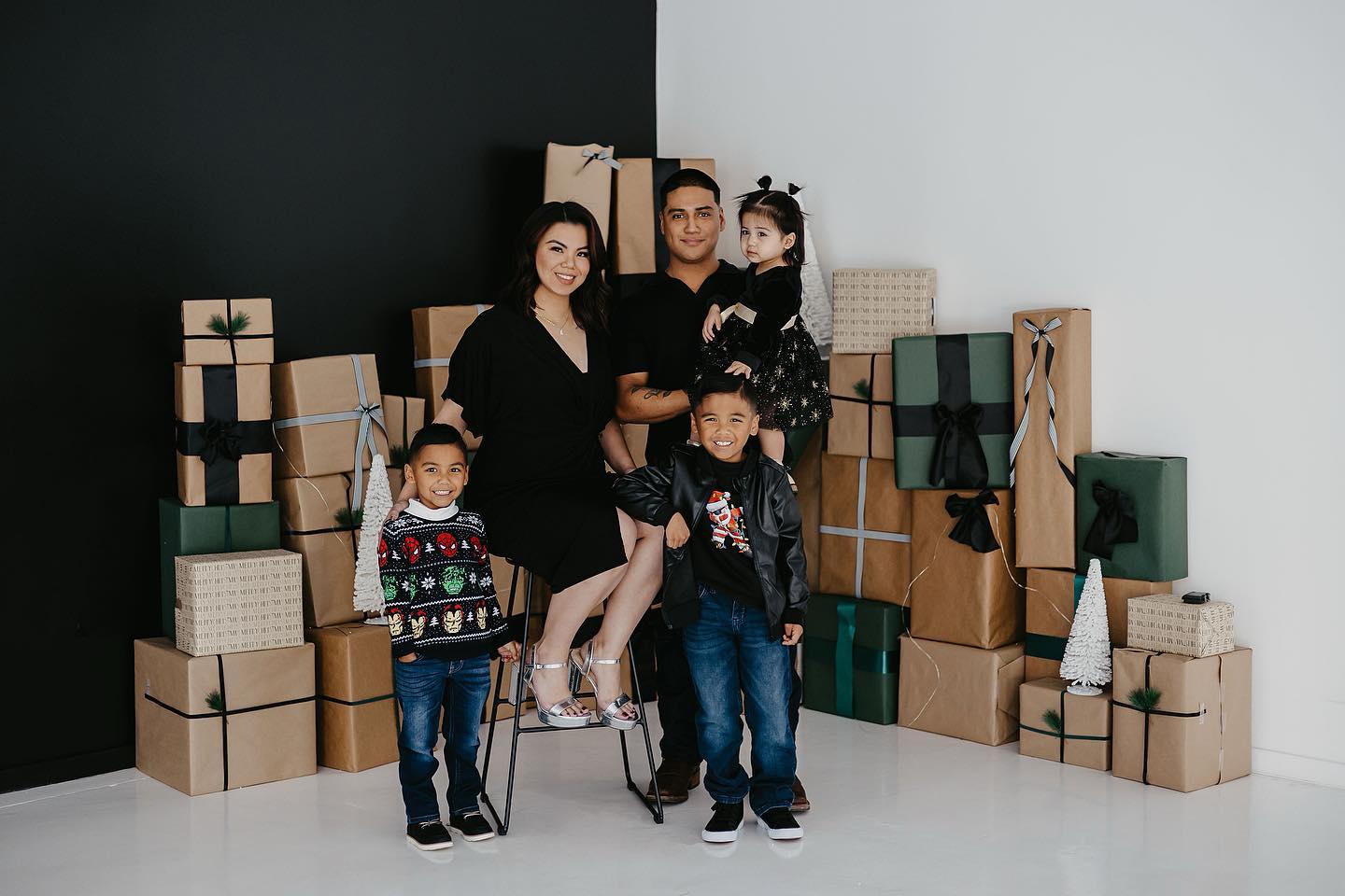 A family posing in front of boxes of presents during Christmas time.