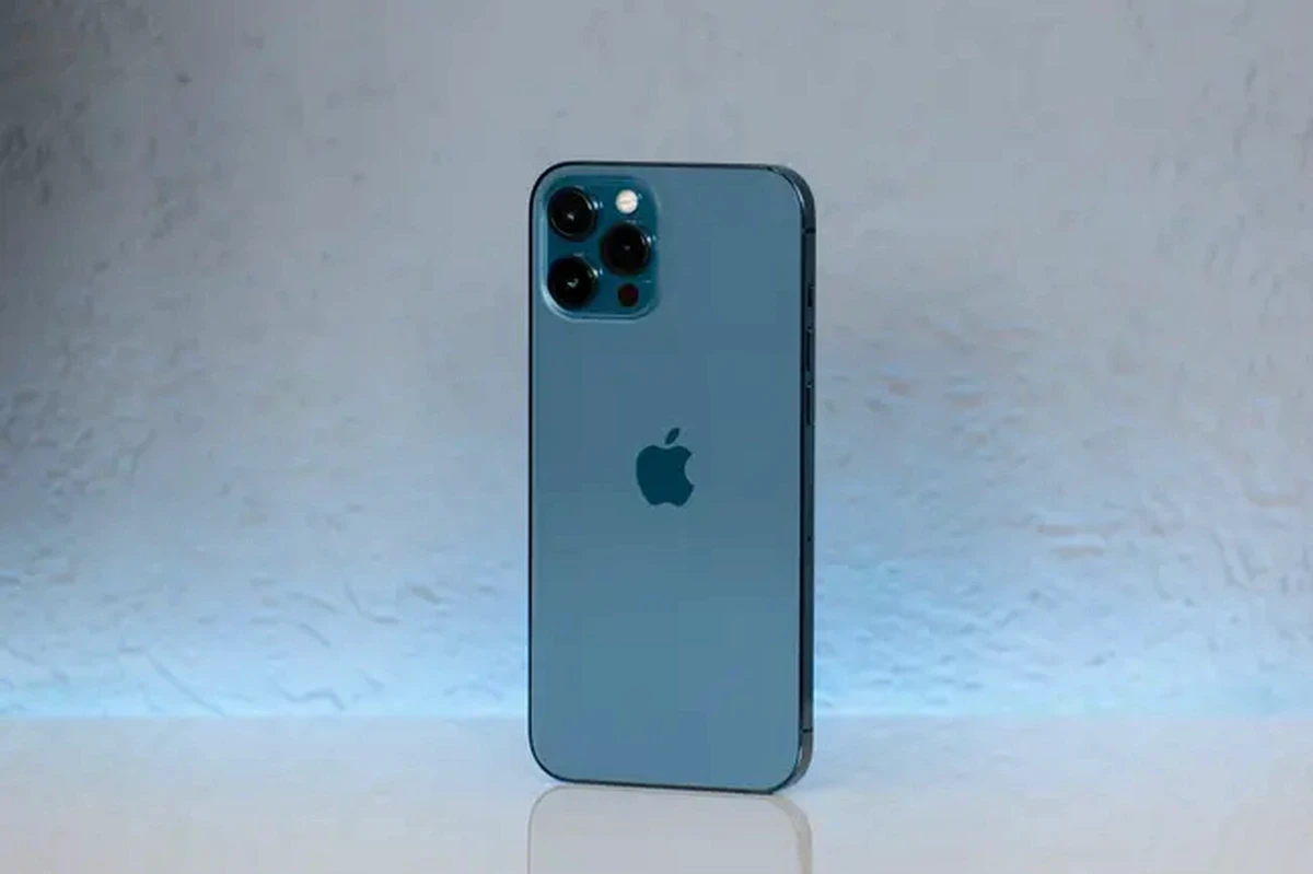 白い表面に立っている青いiPhone、トリプルカメラシステム付き