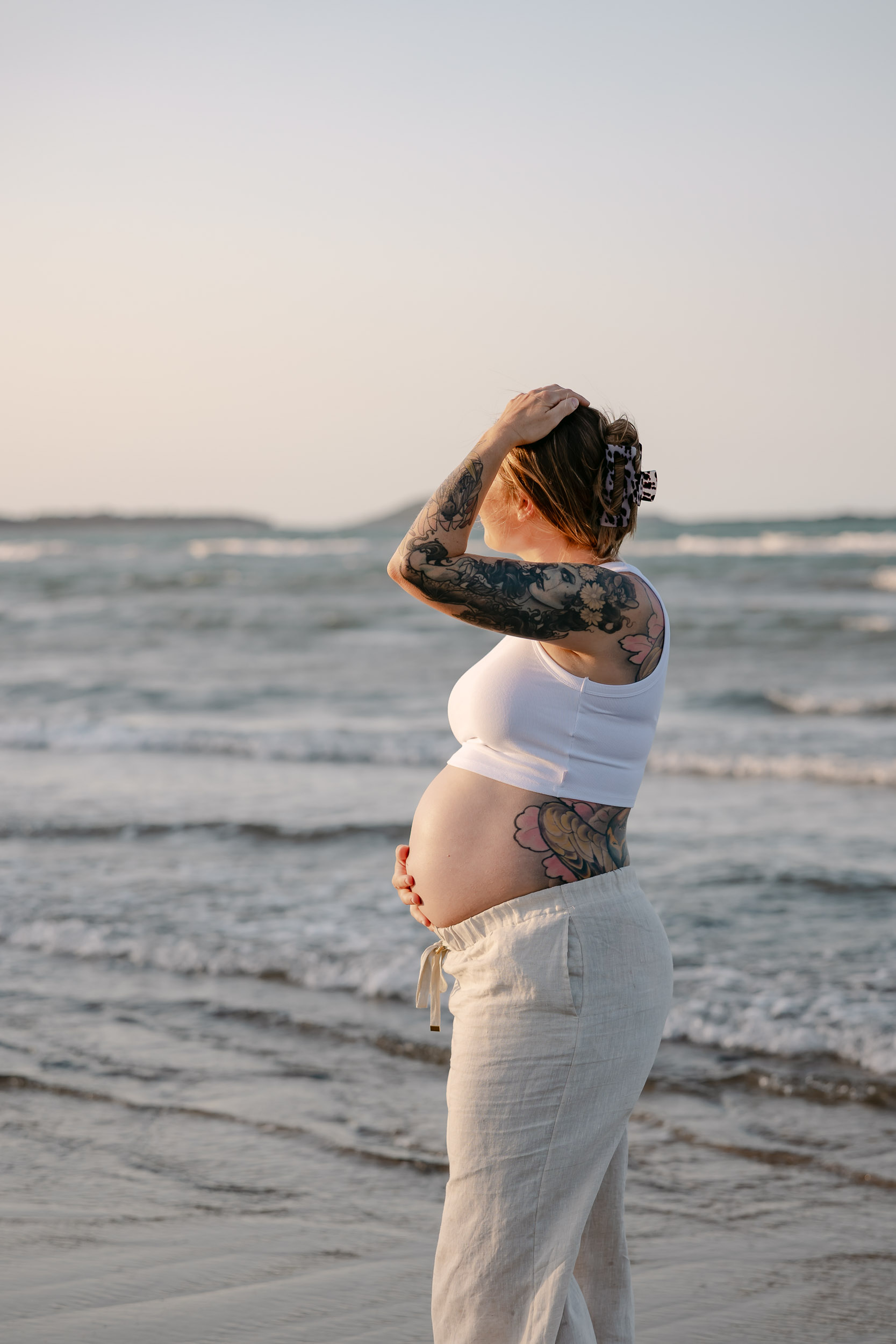 Pregnant woman holding her belly at the beach
