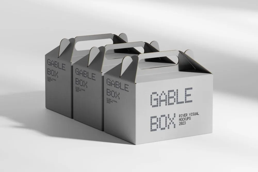 Three gray gable boxes with die-cut handles, neatly aligned on a soft blue surface, illuminated by natural light to emphasize their minimalist and practical design.