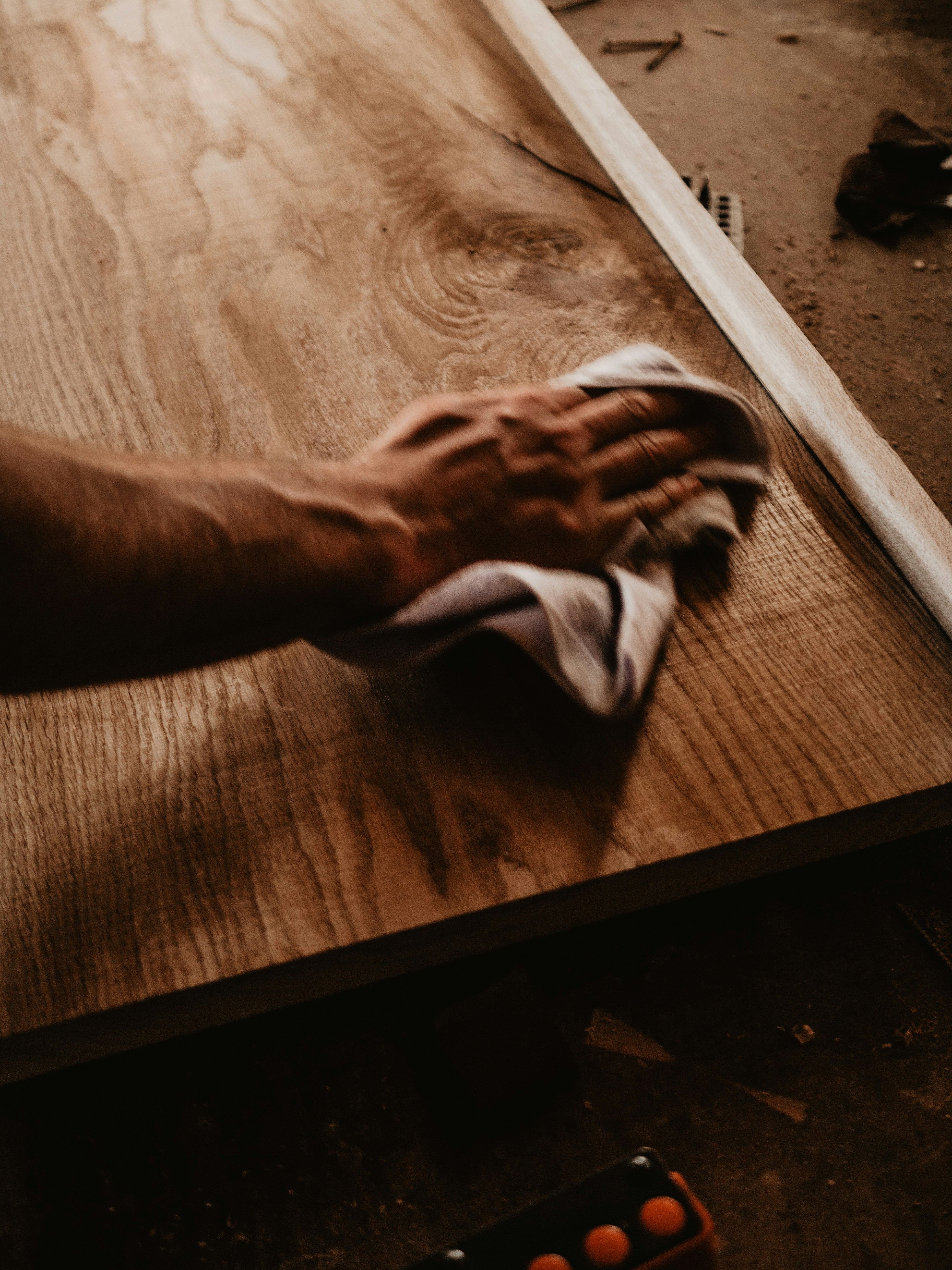 a person wiping up a piece of wood