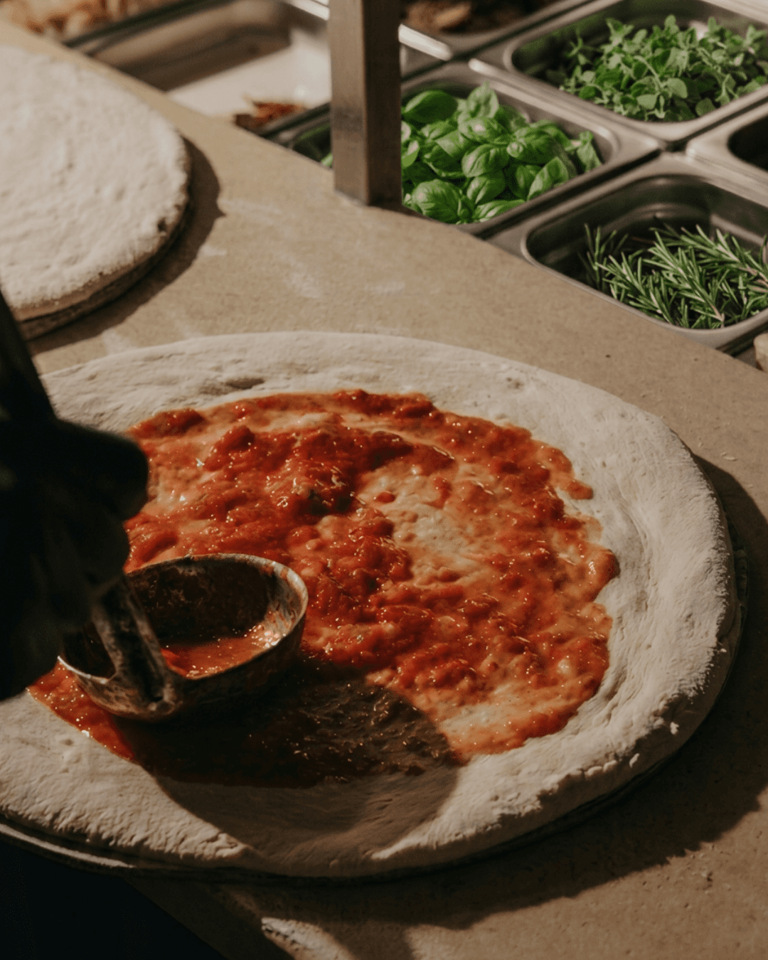 Chef preparing a wood-fired pizza before baking