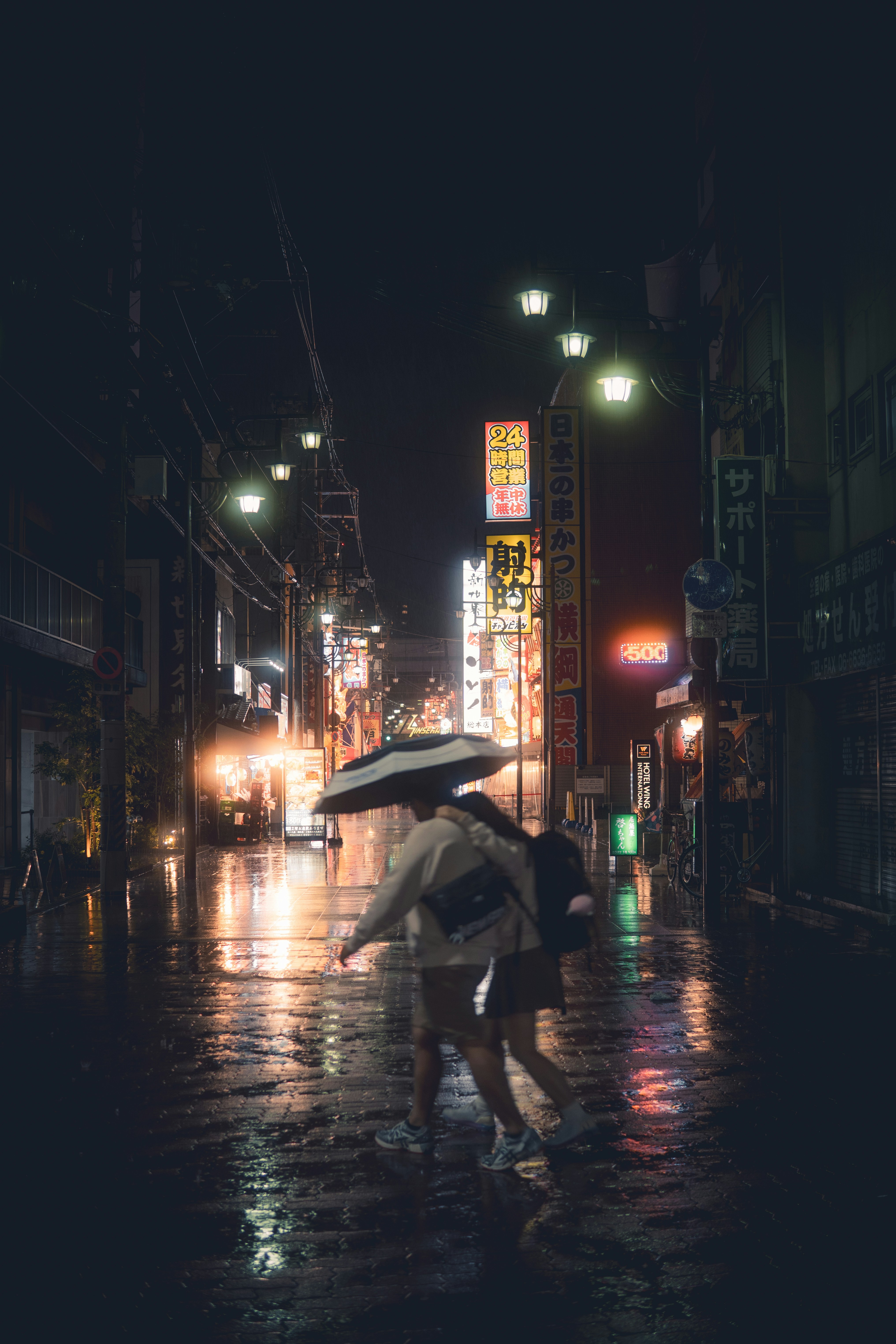 Couple sharing umbrella on wet city street at night