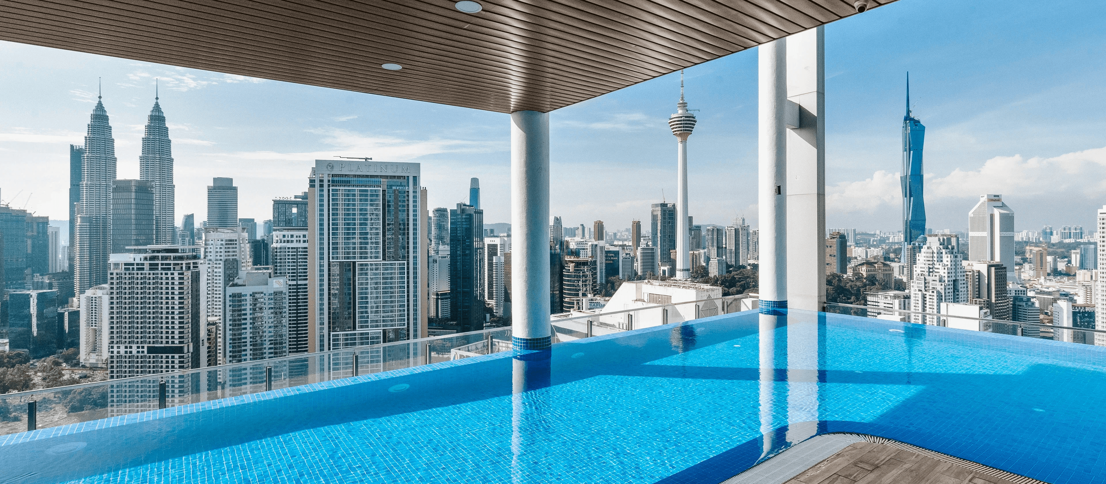 Rooftop infinity pool with sweeping panoramic view of Kuala Lumpur city skyline including Petronas Twin Towers and KL Tower — Airbnb property photography