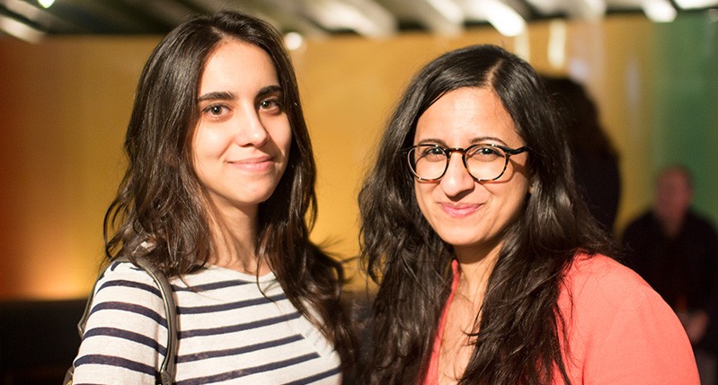 portrait of two woman, one in a white shirt with stripes and one with an orange shirt
