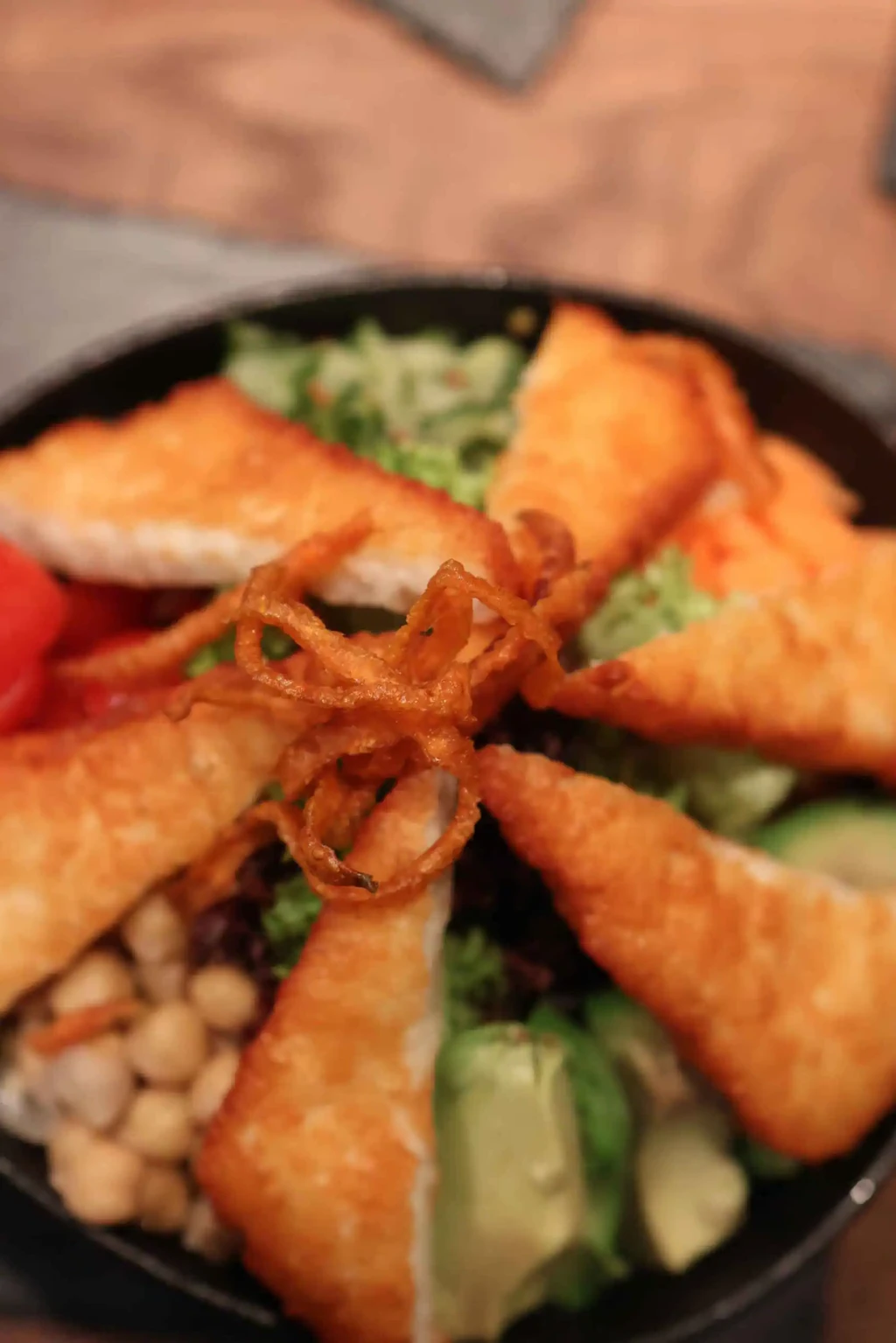 Knusprige Teigtaschen auf frischem Salat mit Gemüse, Kichererbsen und frittierten Zwiebeln im kAlps.