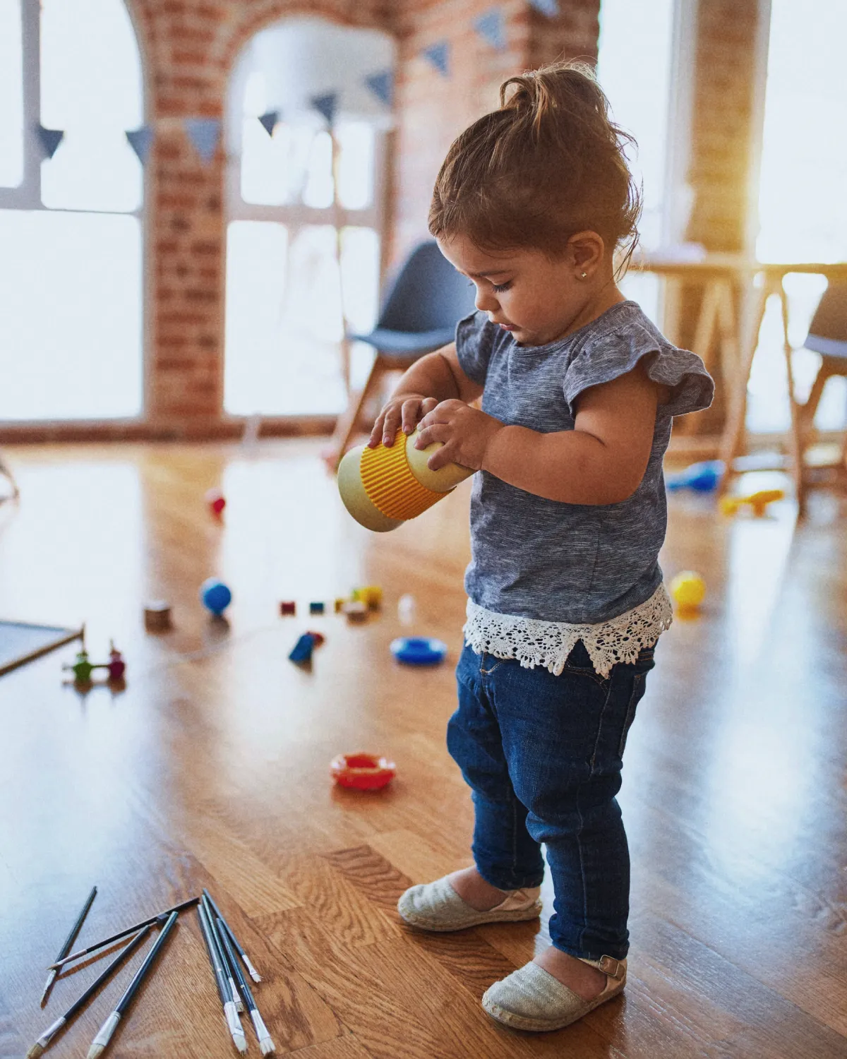 Little girl playing with a yellow toy cup in the clinic facility