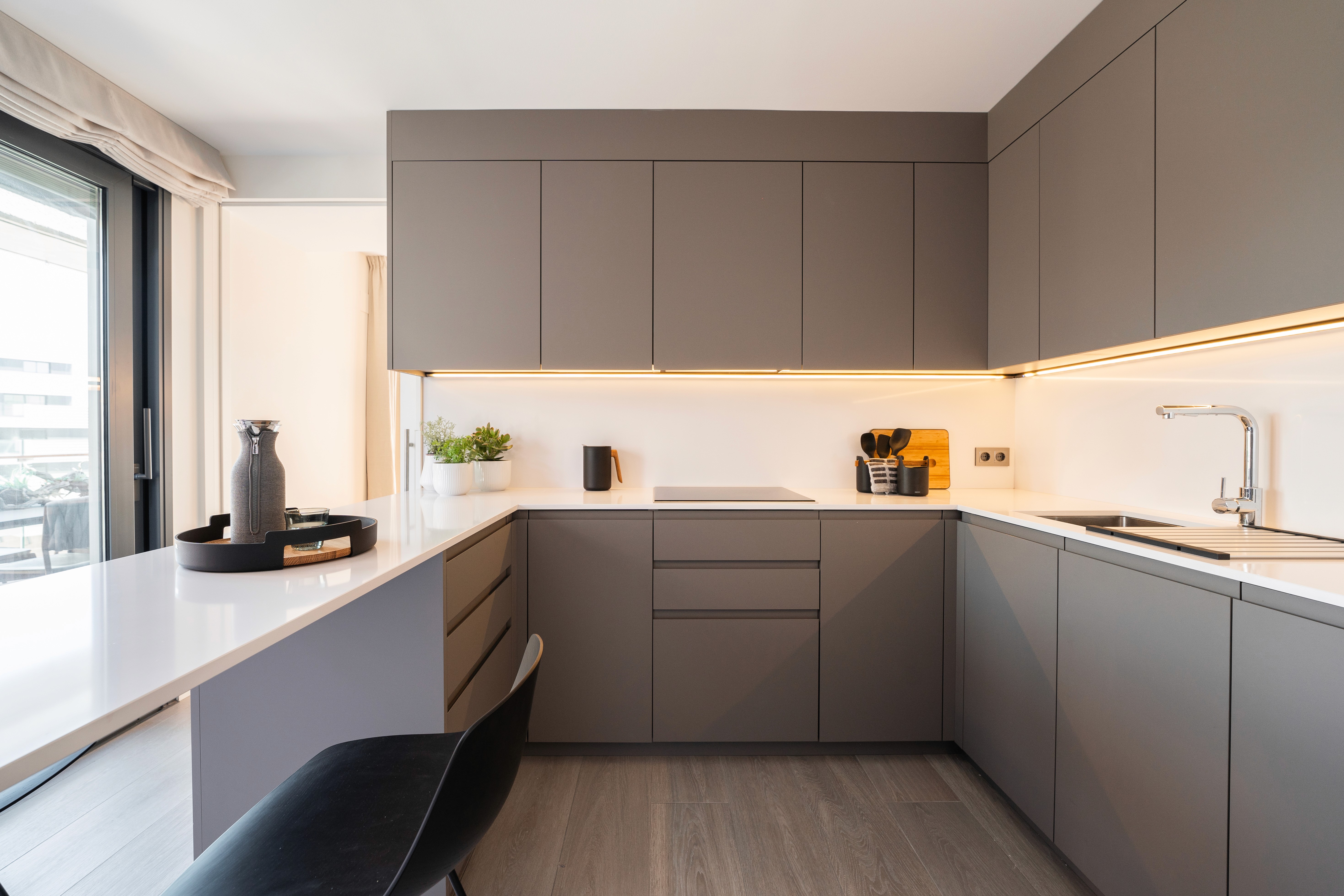 Cocina con muebles gris oscuro y encimera blanca