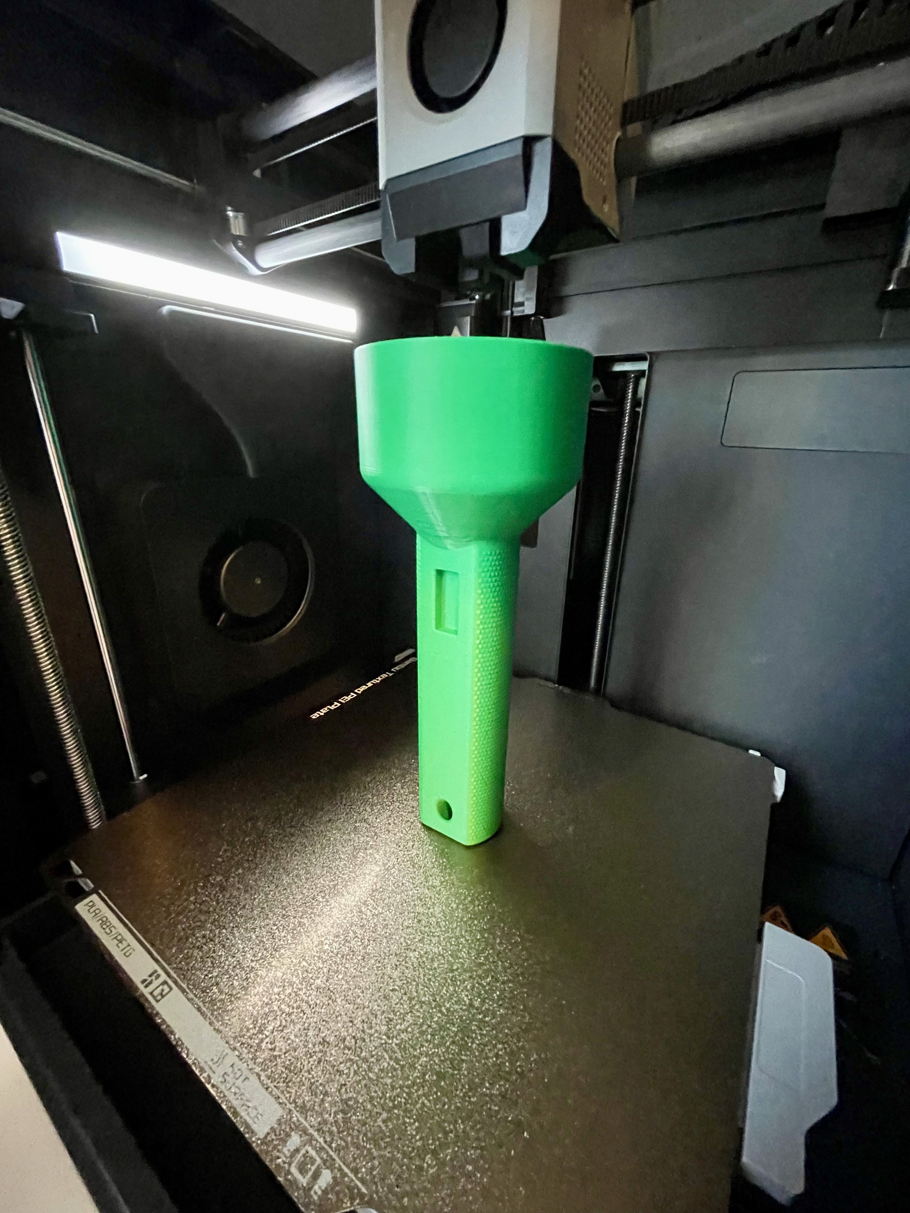 A 3D printer fabricating a flashlight concept, showing the transition from digital design to physical testing.