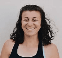 Liz, a white woman with curly brown hair wearing a black tank top, smiling warmly at the camera.