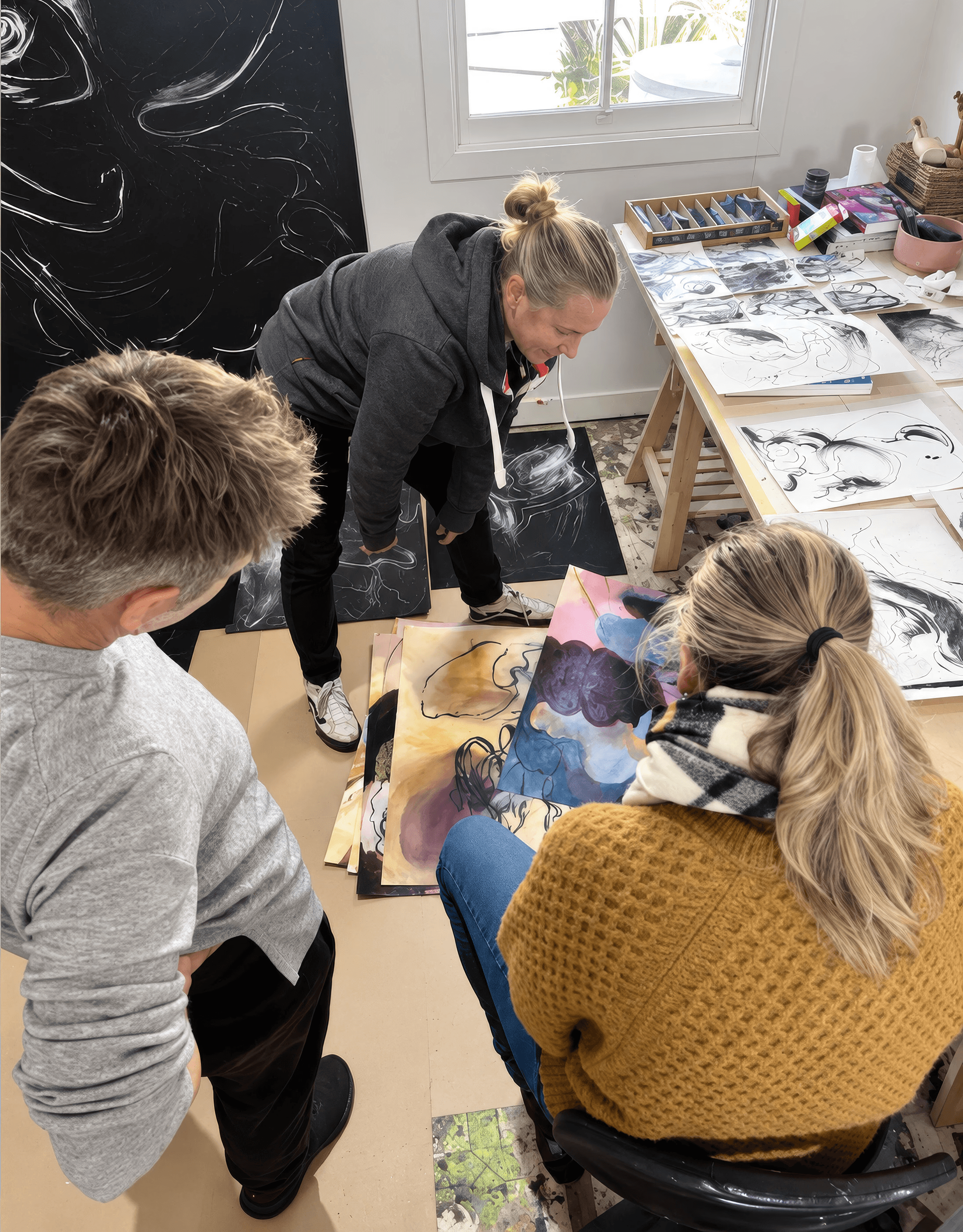 Artists working on drawings around a long table