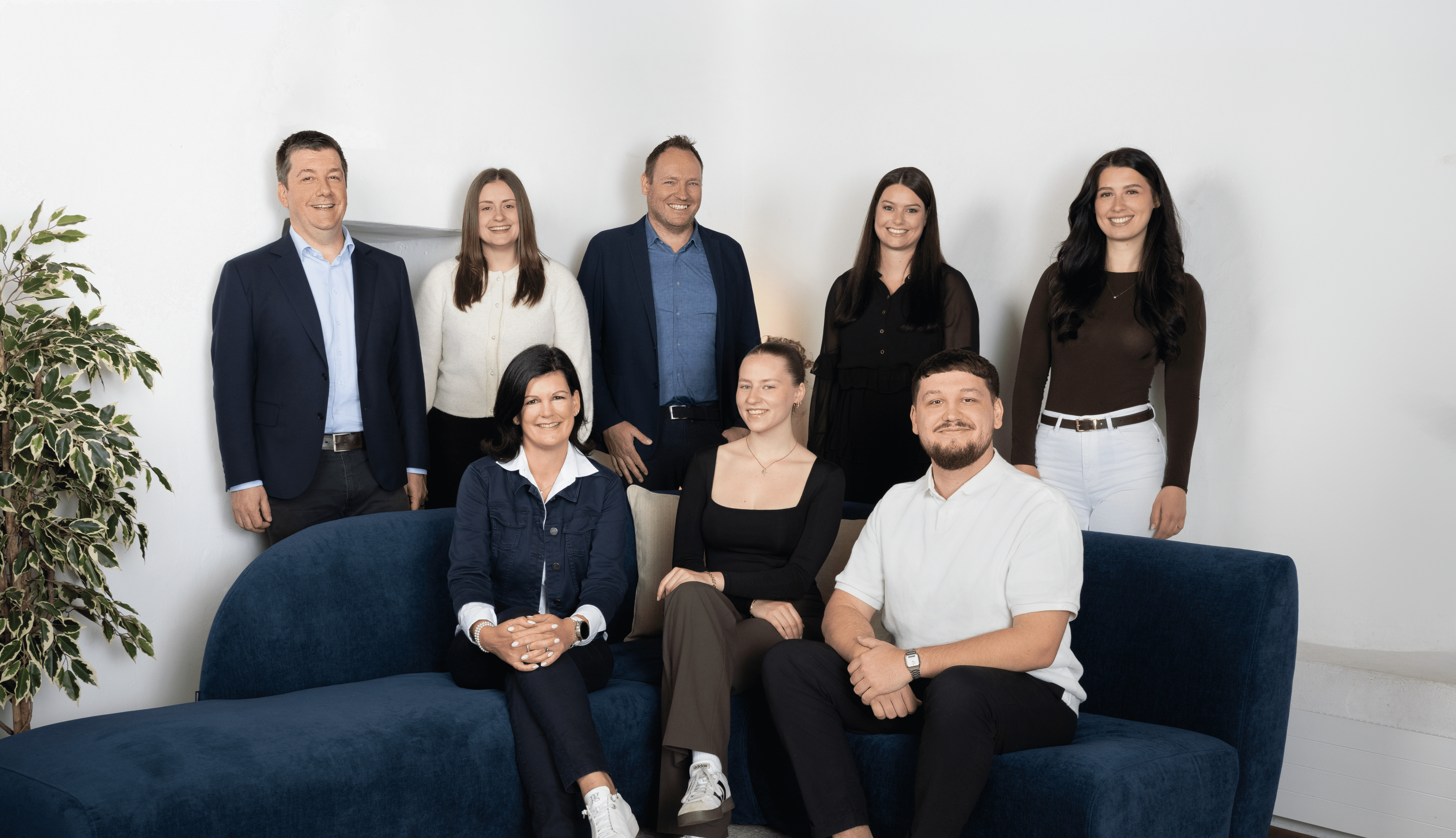 Gesamtes Team von Kocher Immobilien sitzt gemeinsam im Büro und lacht in moderner Umgebung