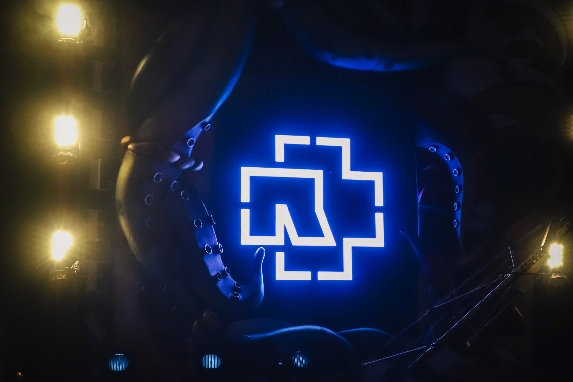 Logo du groupe Rammstein illuminé de bleu, entouré d'une sculpture de dragon