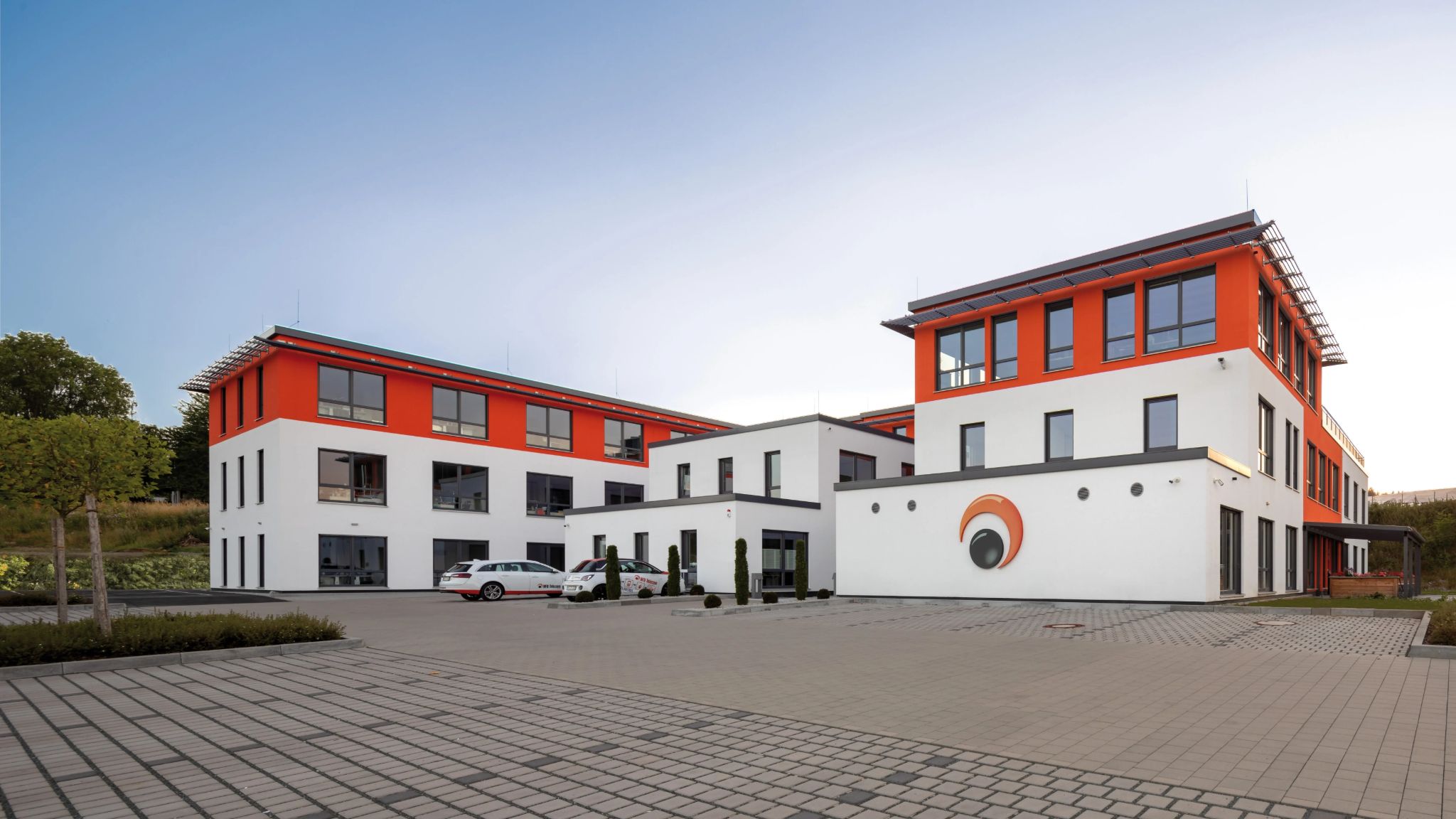 Außenansicht auf Bürogebäude mit Parkplatz davor.