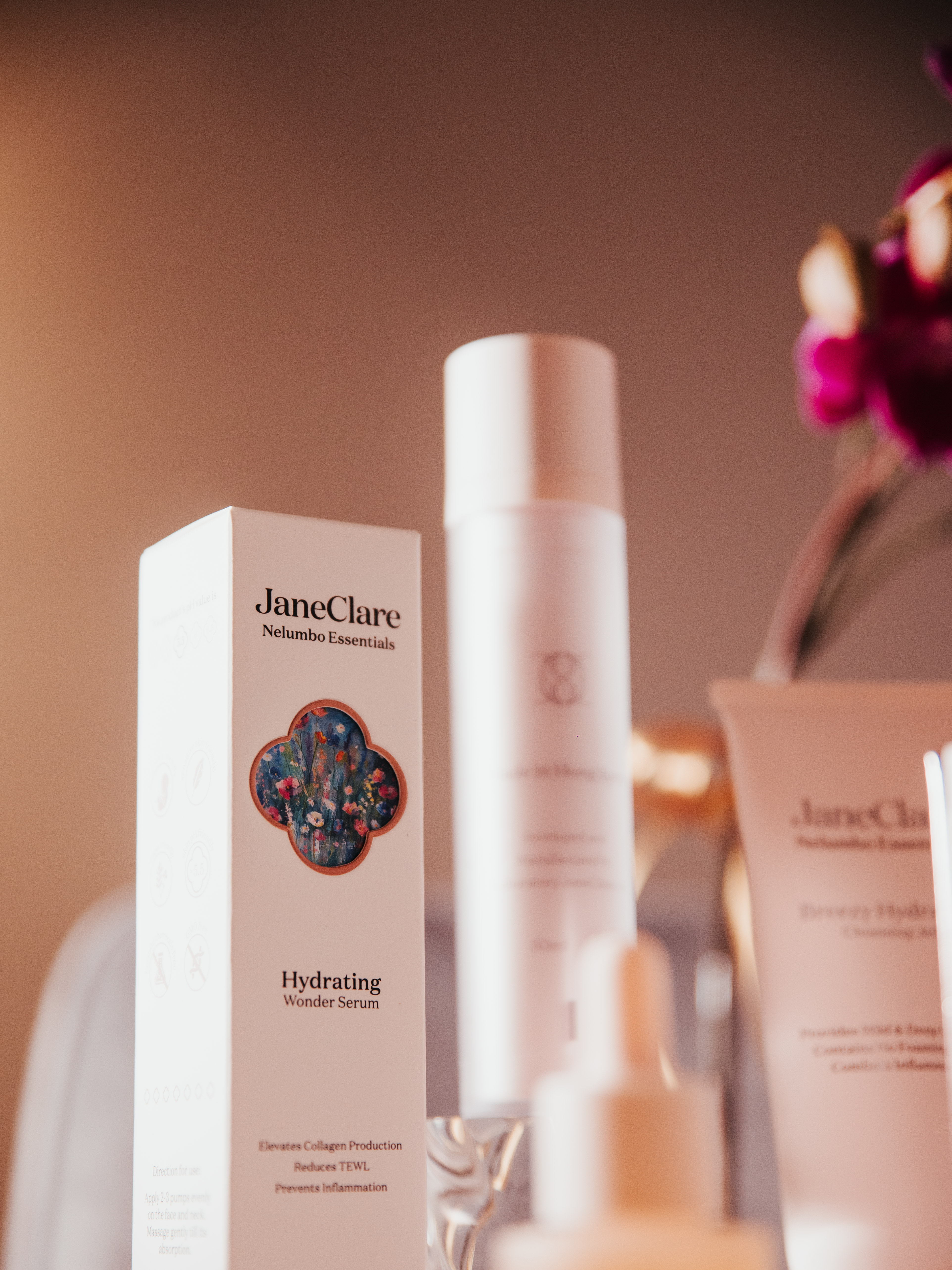 JaneClare Hydrating Wonder Serum and skincare product line in elegant packaging with floral background.