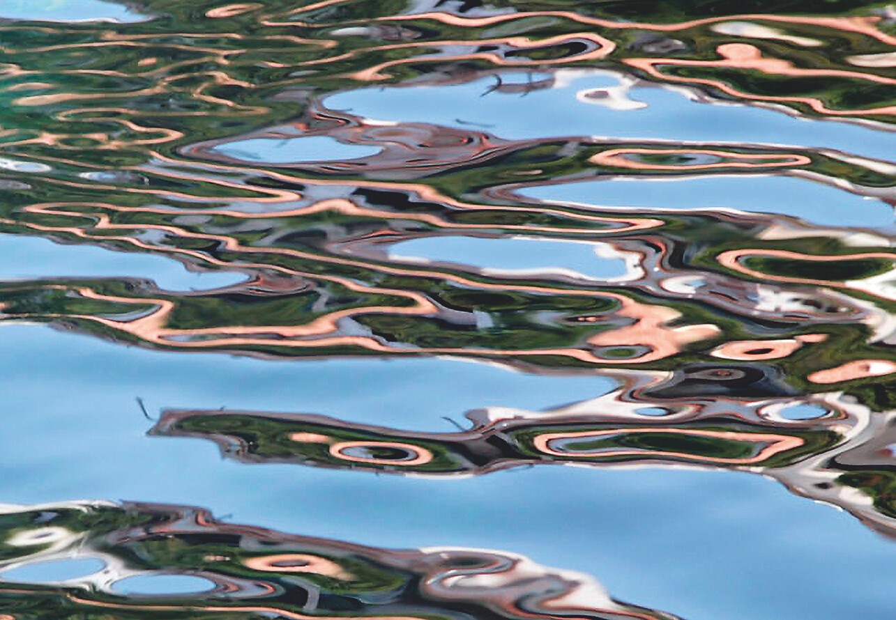 Wellen mit breiten Spiegelungen von blauem Himmel und rosa Lichtbändern