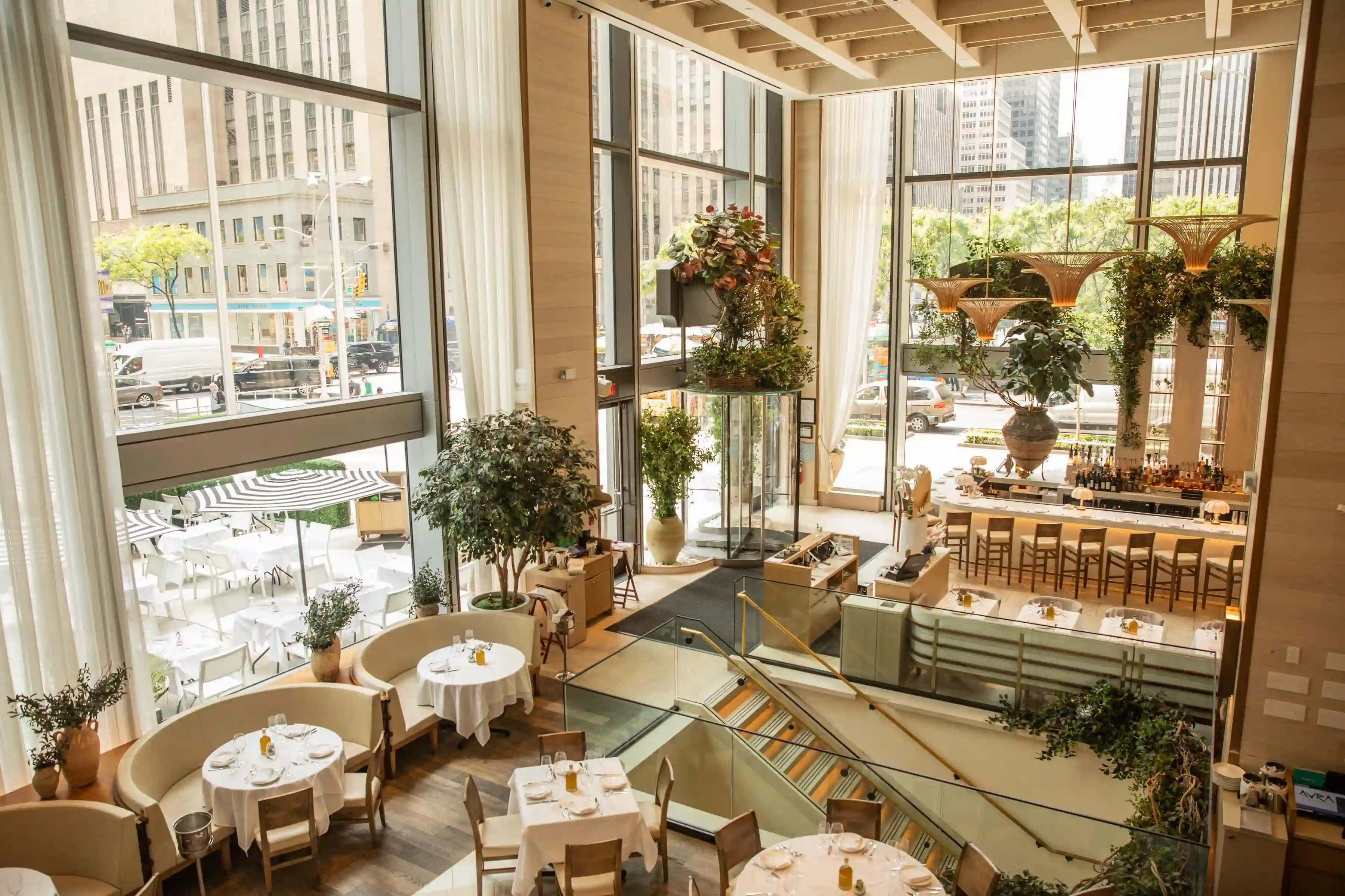 A stylish, modern café interior with wooden beams, plants, and comfortable seating, filled with natural light.