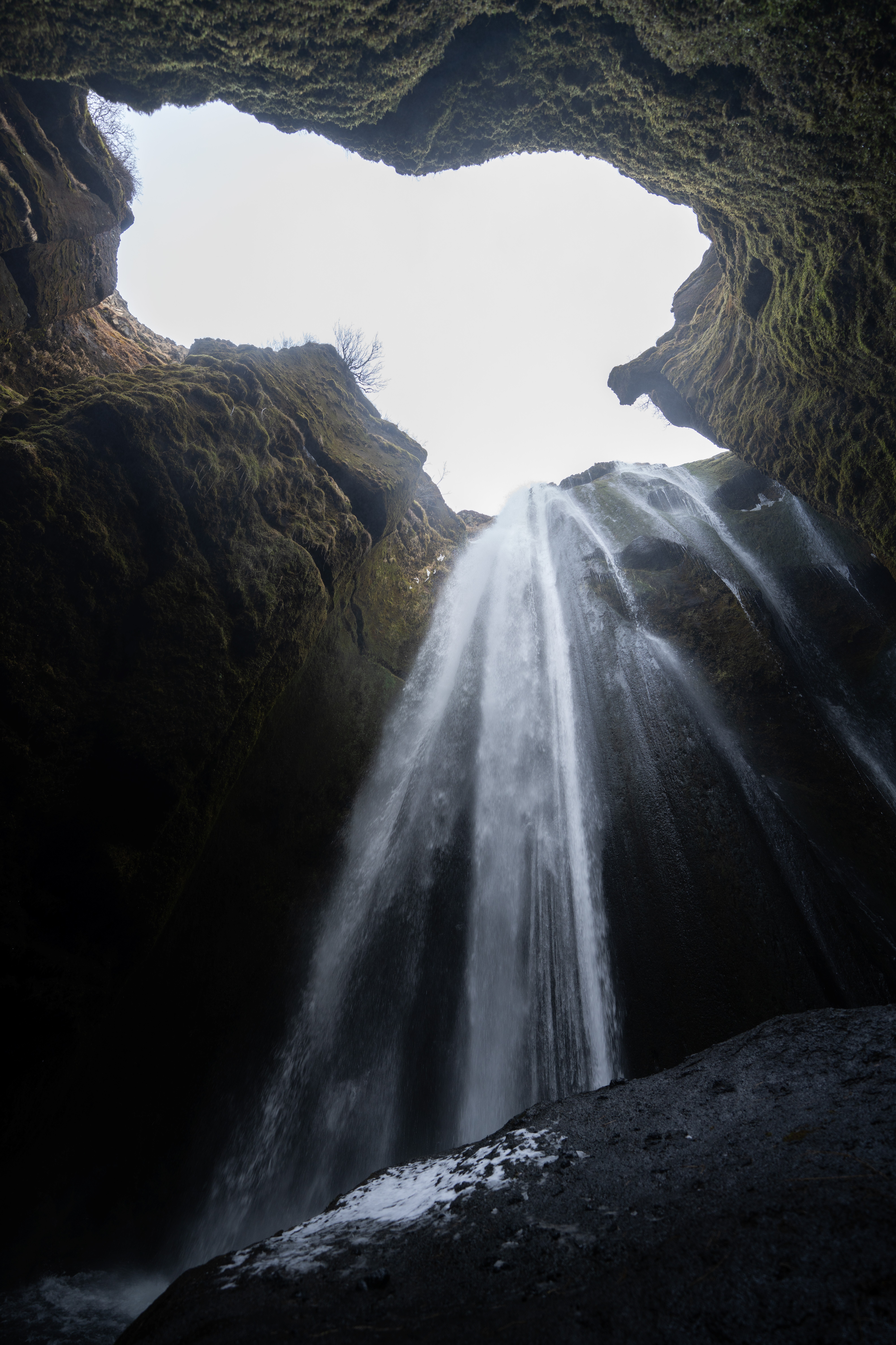 Looking up at a powerful waterfall between mossy cliffs on the South Coast