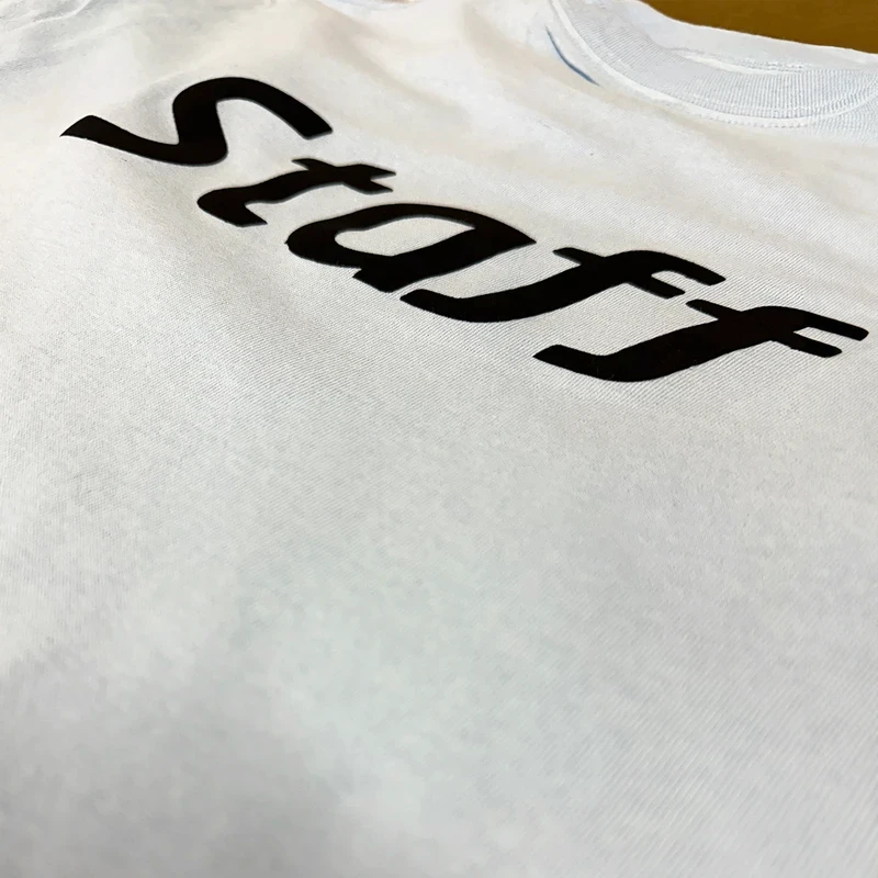 Close-up of white fabric with bold black 'Staff' text