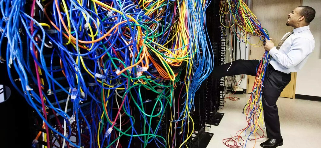 a frustrated man standing in front of unorganized internet cables.