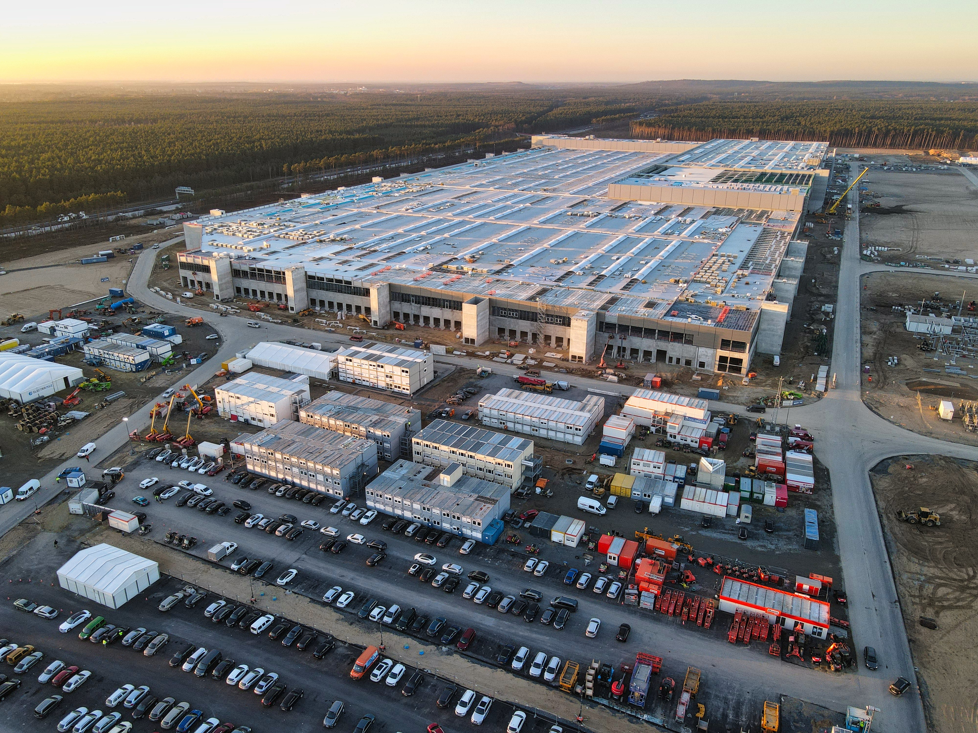 A woman with red hair and a black sleeveless top smiling confidently in a bright, modern indoor setting.