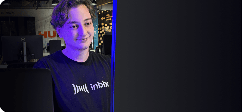 Smiling person in an Inbix T-shirt at a computer, with a tech-themed background. Represents Inbix's corporate education platform.