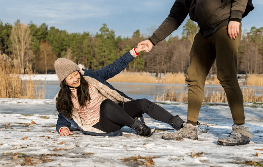 woman smiling being helped up from slipping on ice