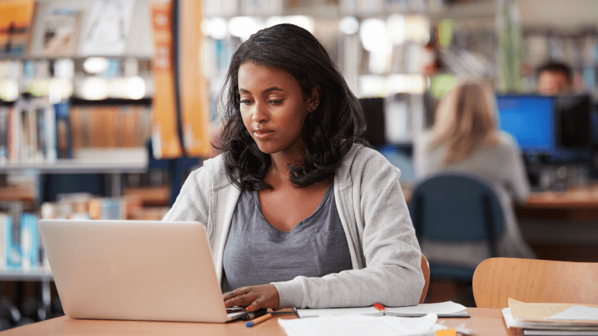 Ethiopian high school student conducting original research at a desk with academic journals and a laptop