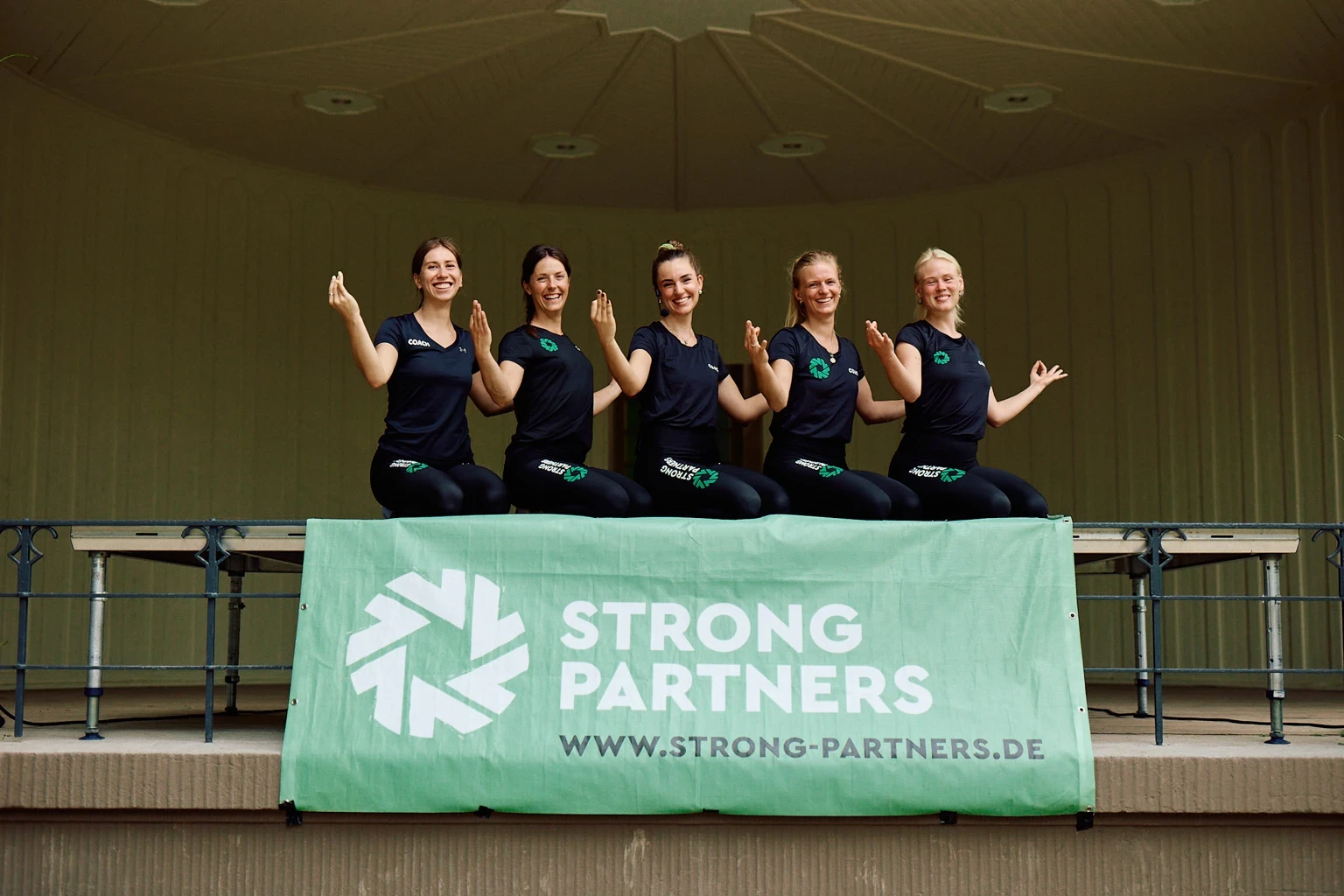 Strong Partners Trainerinnen stehen in einer Reihe und machen eine Yoga-Pose