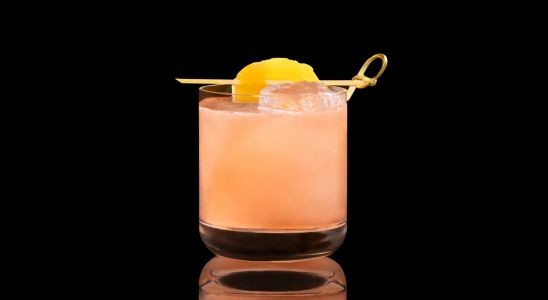 A closeup of a Sweet, Spring Tropical Peach drink against a dark background.