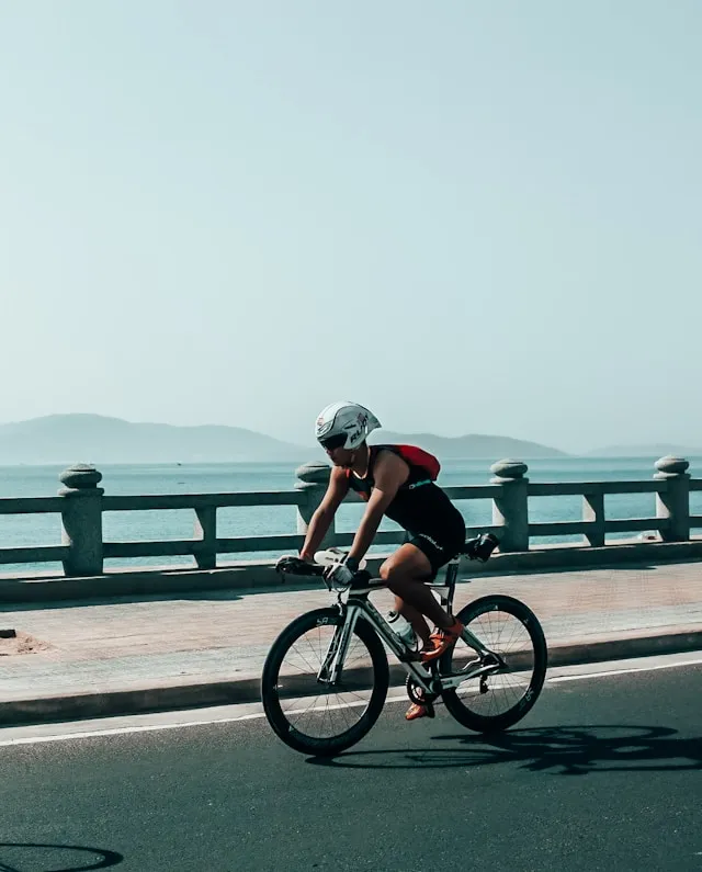 Cyclist riding along a waterfront road with a calm horizon in the background
