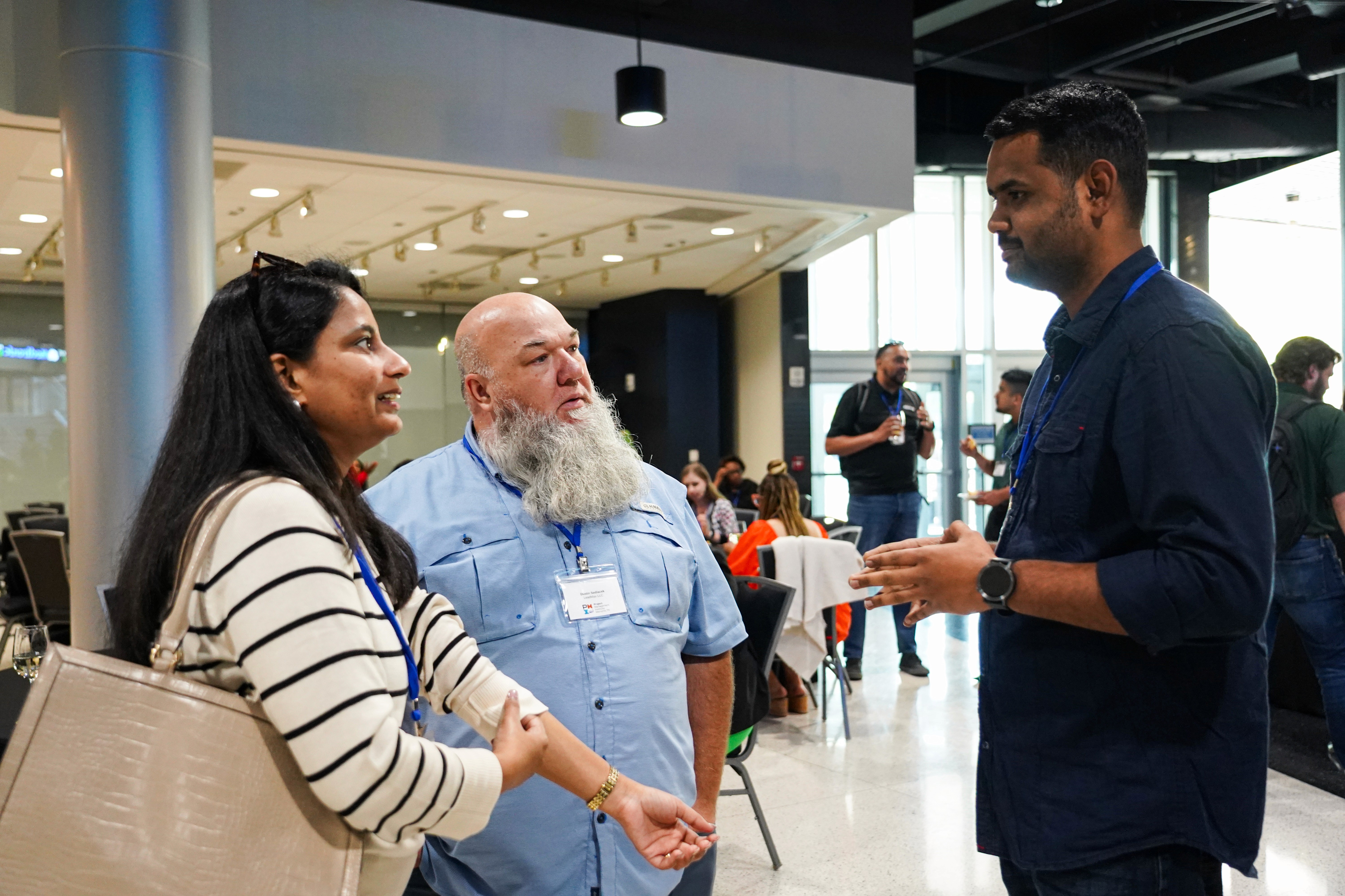 Three people sitting on a couch in a room looking at mobile devices