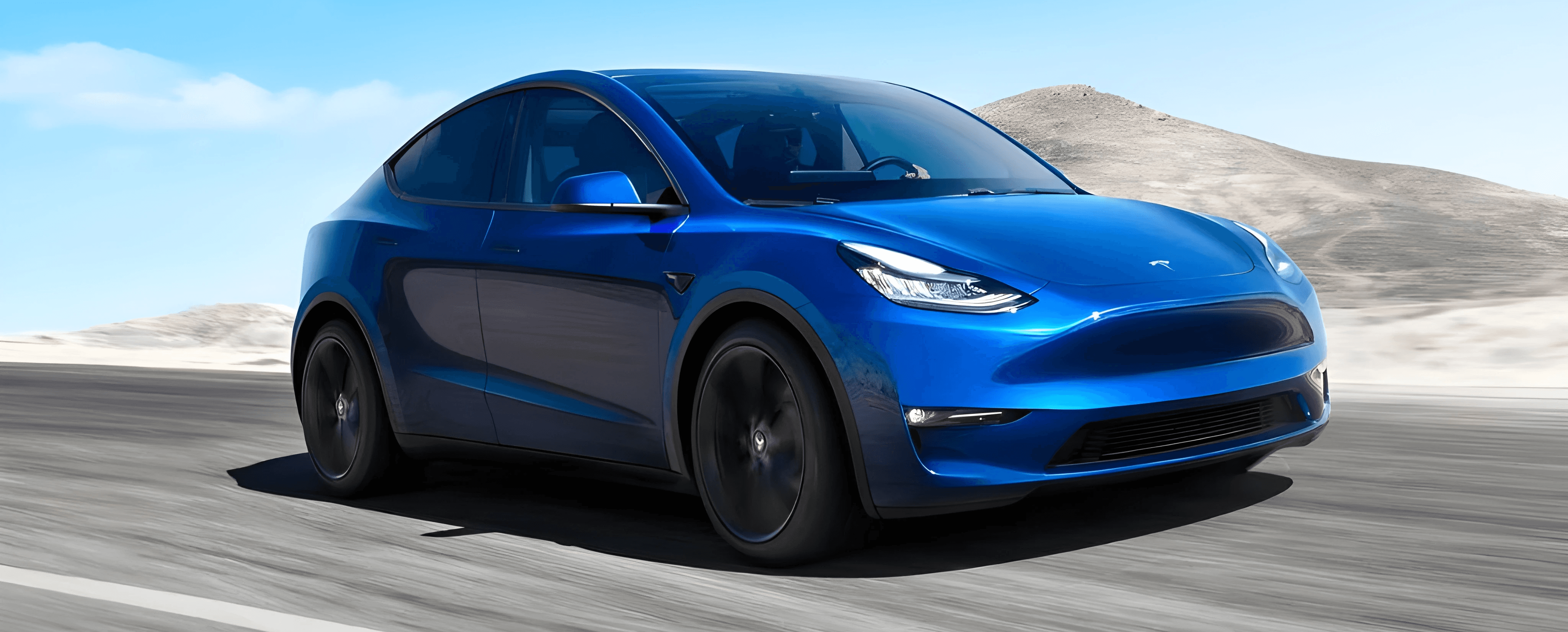 Tesla Model Y bleue sur route ouverte, SUV électrique vu de face dans un décor minéral et ensoleillé
