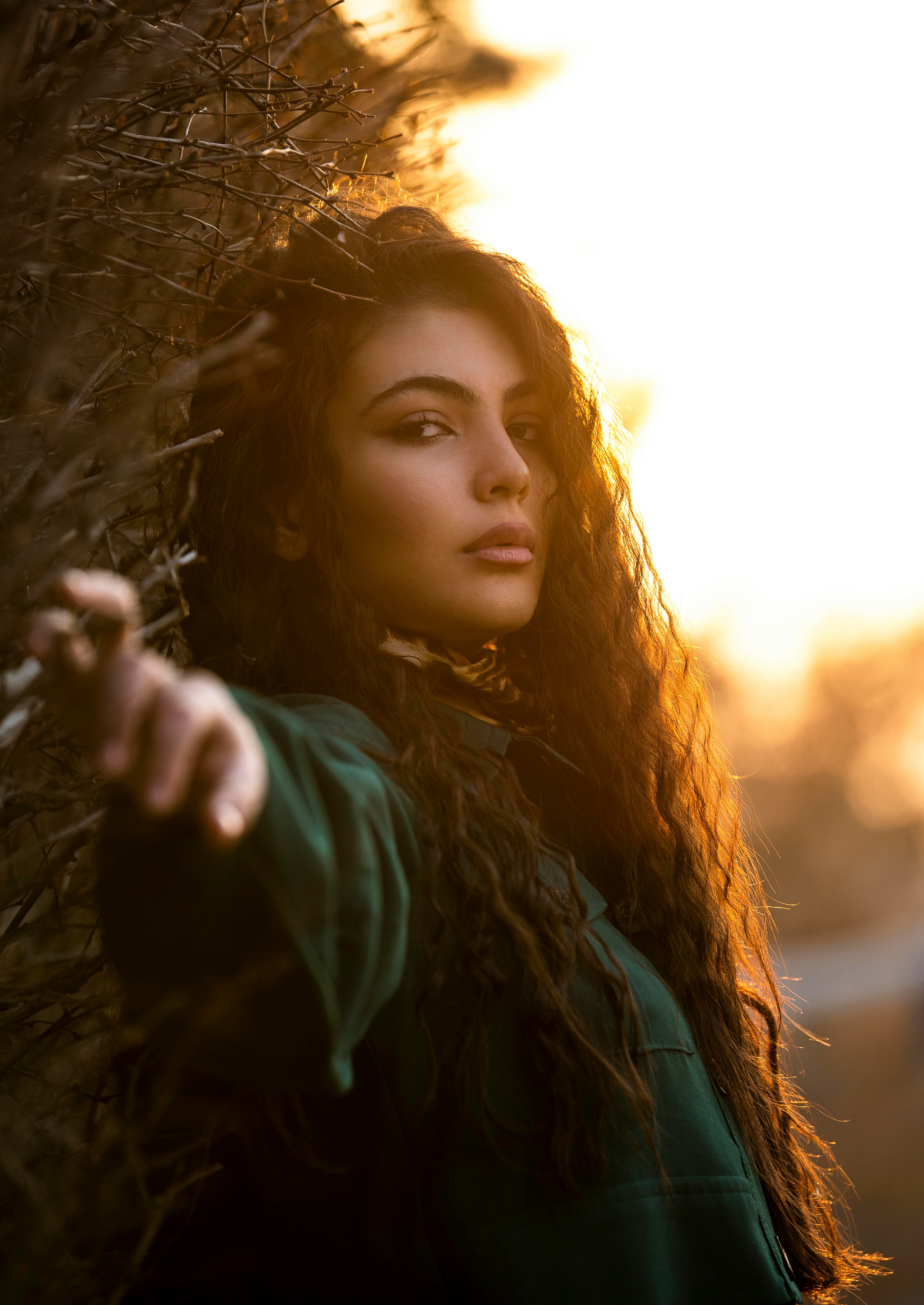 a woman with long hair standing in front of a tree