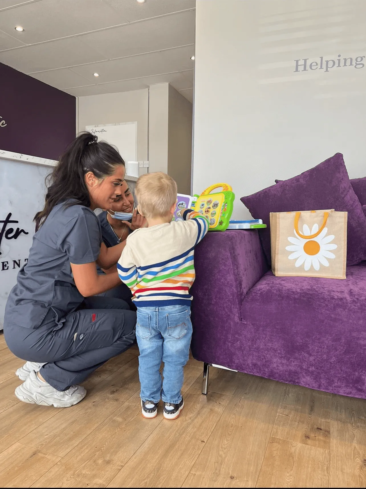 Sophie, our dental nurse, sitting and reading a book to a child whilst they visited the practice.