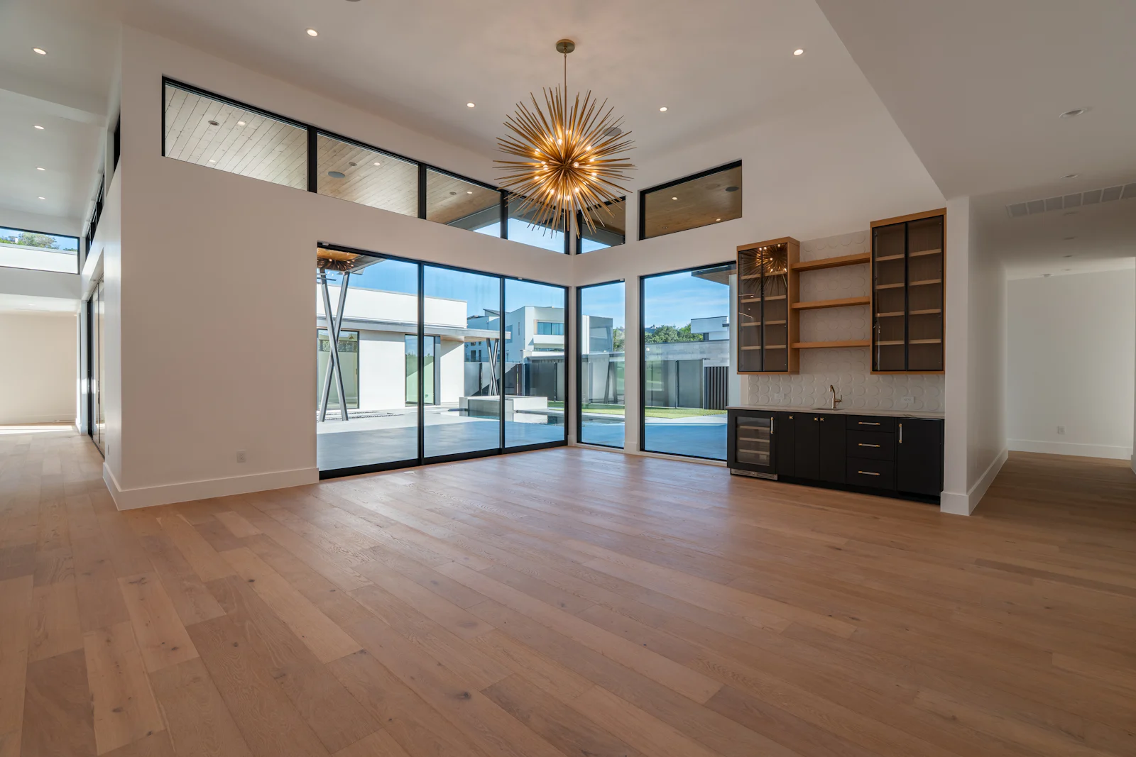Spacious modern room with wood floors, large windows, and bar