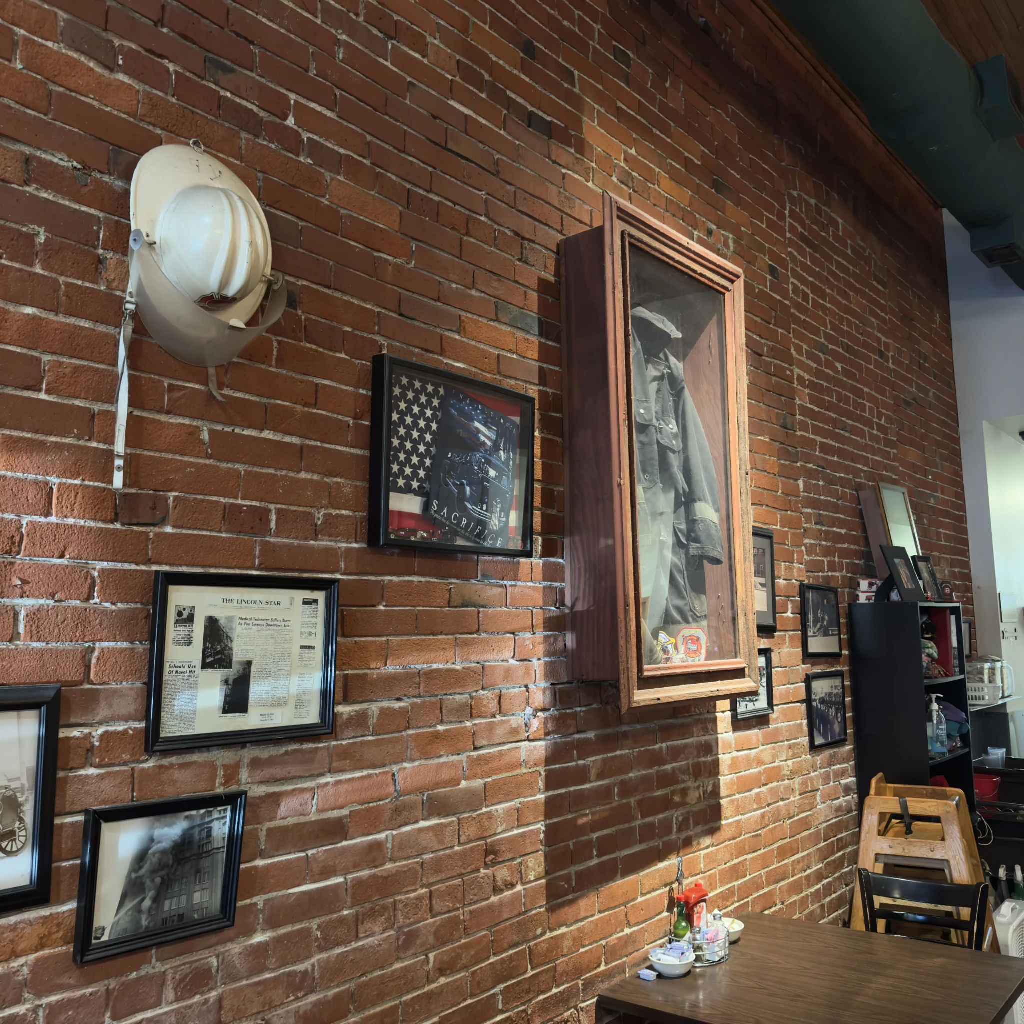 Interior of Engine House Cafe with exposed brick walls and vintage firehouse decor, including a wooden ceiling and framed fire department memorabilia.