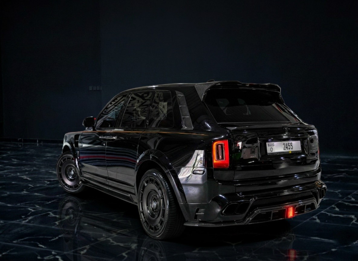 Rear corner exterior of black Rolls-Royce Cullinan Mansory-style 2023, luxury SUV with wide stance, premium wheels, and bespoke styling