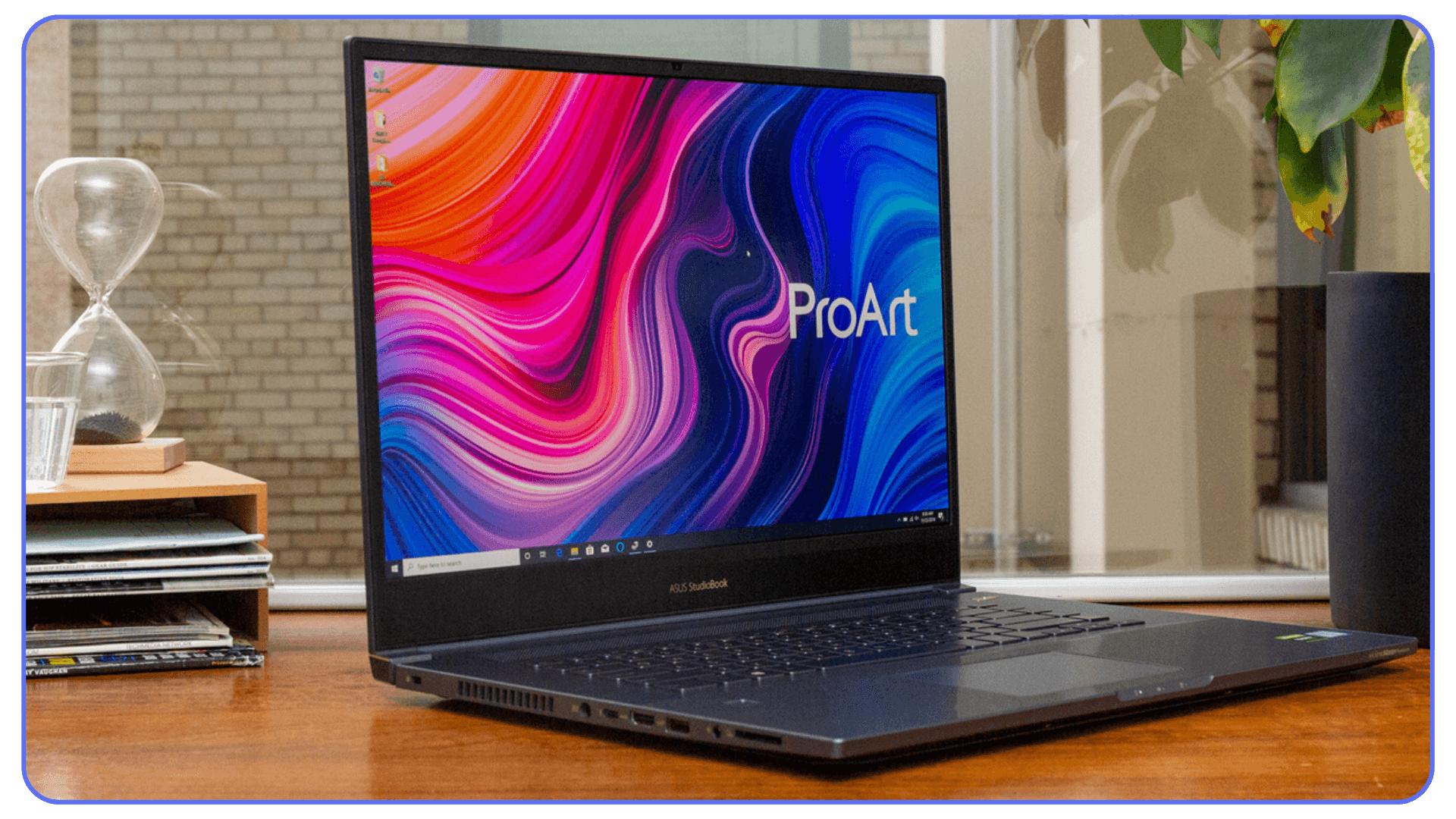 ASUS ProArt laptop opened on a wooden desk with a colorful display.