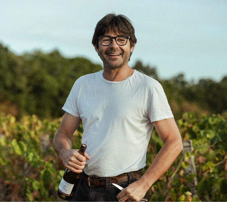 Portrait d'Hervé, une bouteille à la main dans les vignes