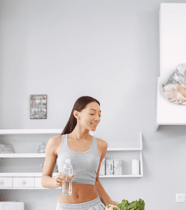 Woman holding water bottle in kitchen