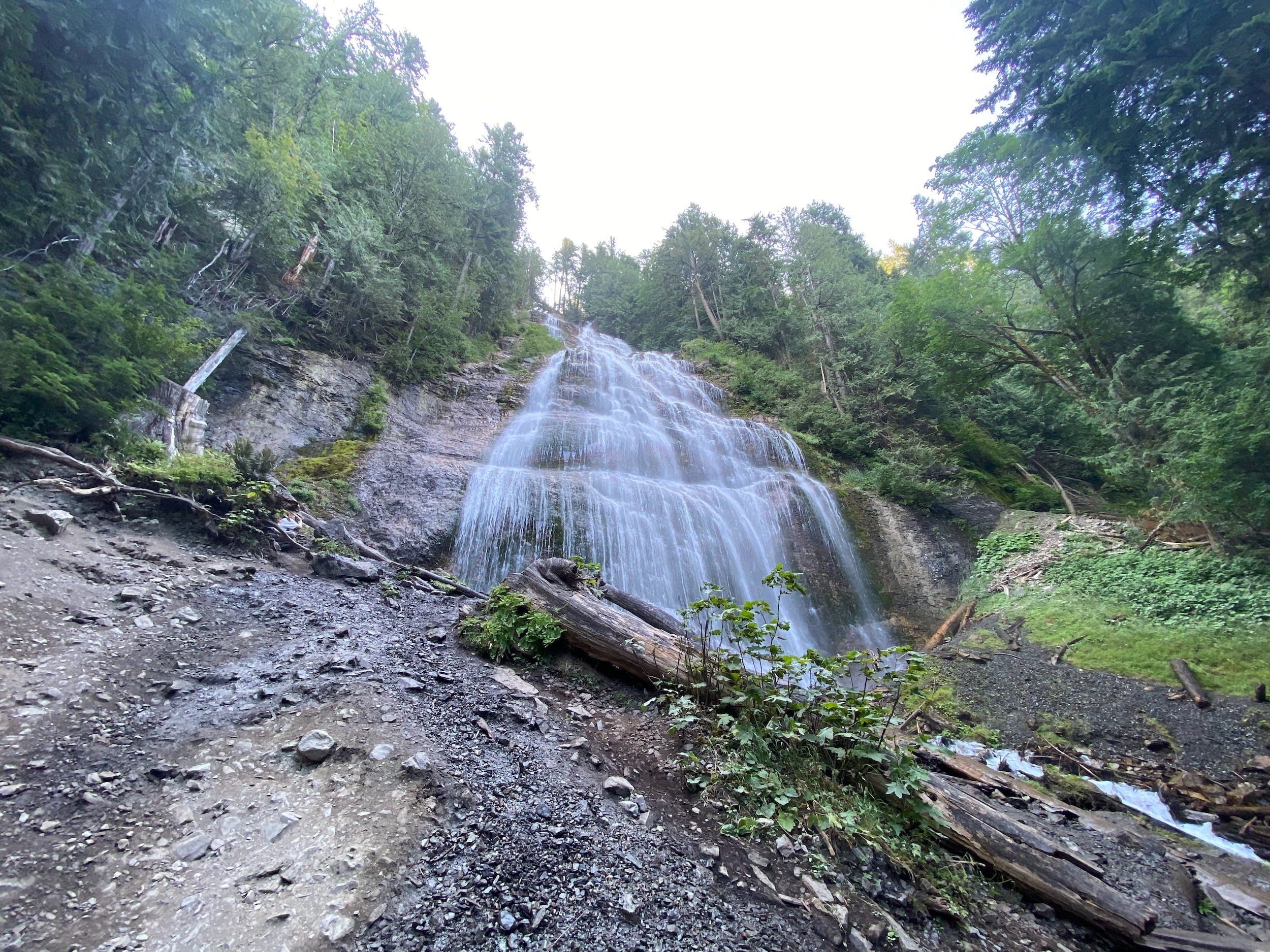 A waterfall spills in white veils down a steep rock face, forest closing in on either side.