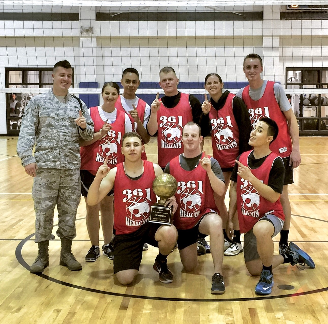 team of volleyball players posing and holding a trophy