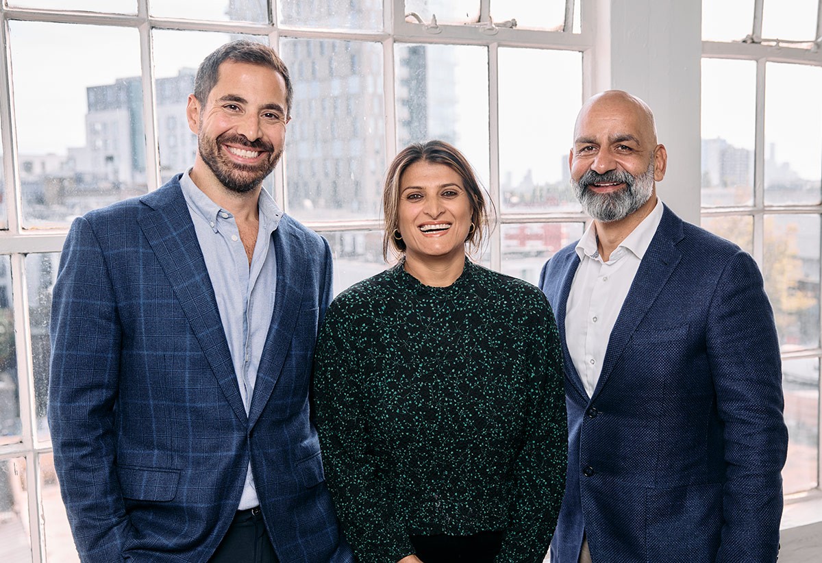 Photo of the three Valliance Founders, Tarek Nseir, Anita Rajdev and Rad Parvin standing together in front of large window