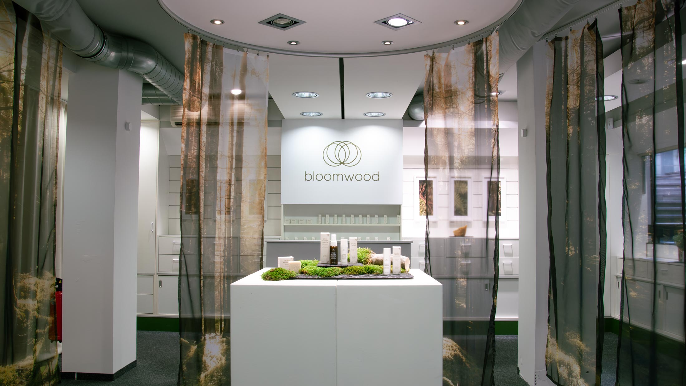 Die Brand Identity wurde in einen Pop-up-Store übertragen. Transparente Stoffe mit Waldmotiven greifen die Bildsprache auf und schaffen eine atmosphärische Verbindung zum Ursprung der Produkte. Eine reduzierte Präsentation auf Podesten lenkt den Fokus auf Materialität, Qualität und die ruhige Tonalität der Marke.